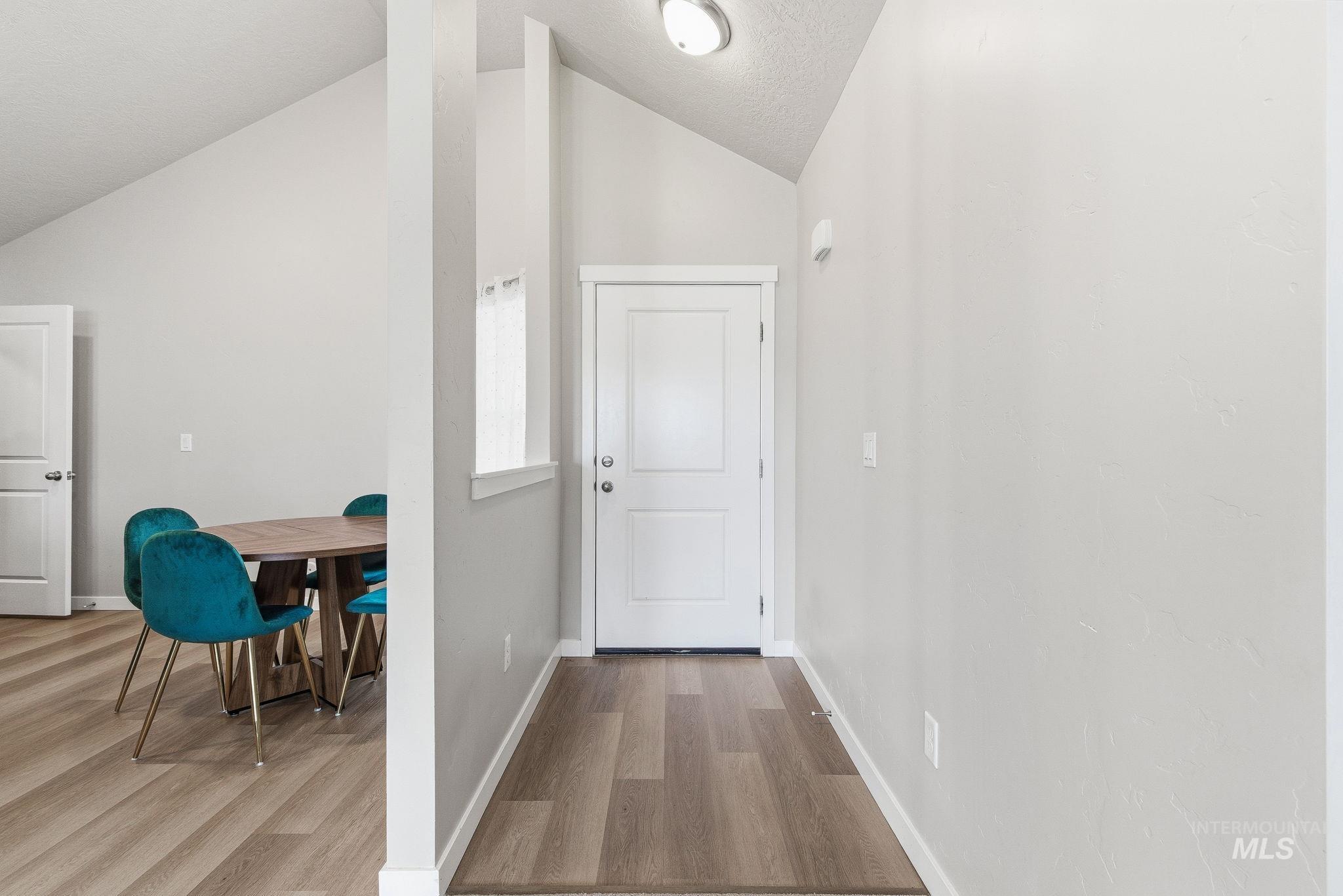 Hall with light wood-type flooring and lofted ceiling