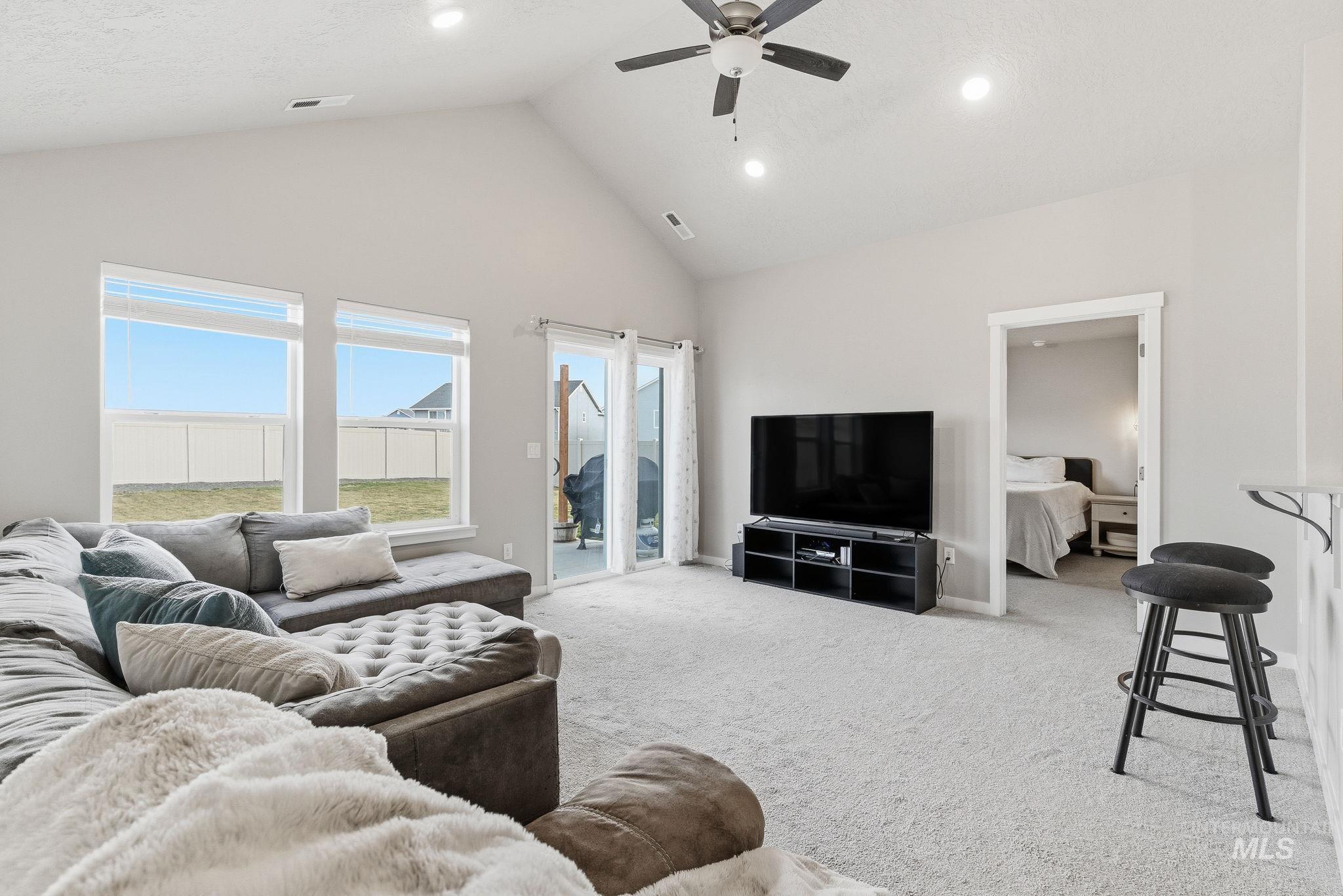 Living area featuring high vaulted ceiling, light carpet, ceiling fan, and recessed lighting