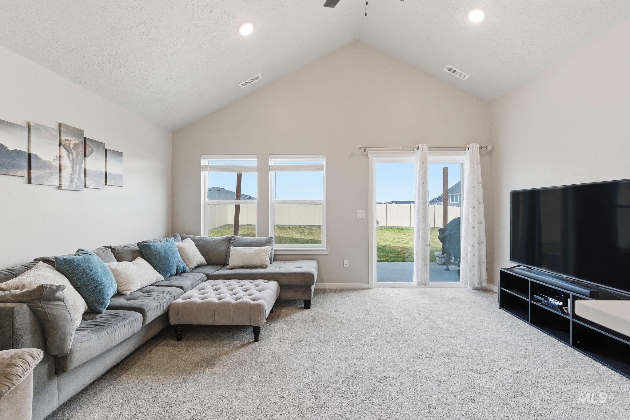 Living room featuring a ceiling fan, light colored carpet, high vaulted ceiling, and recessed lighting