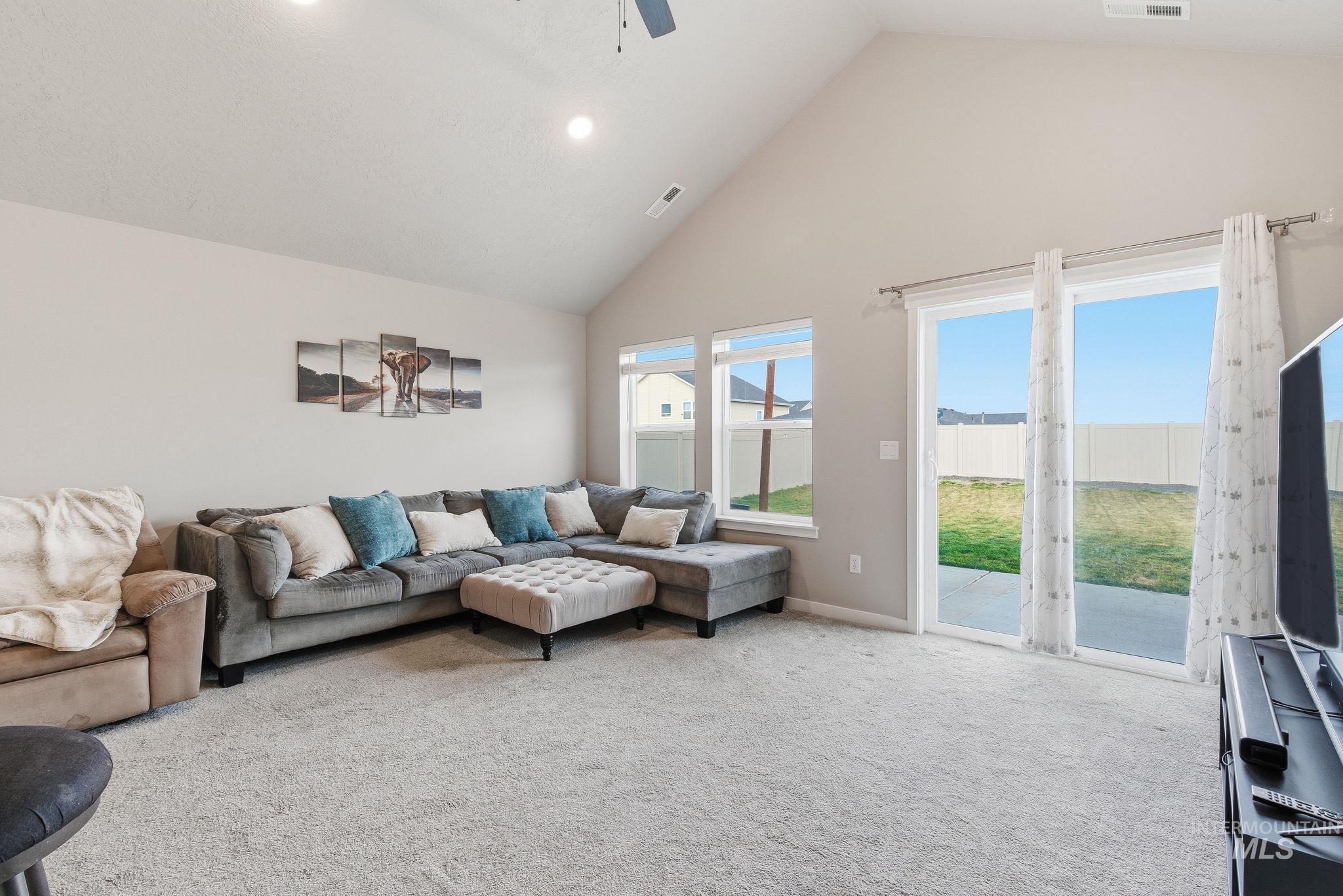 Living room with high vaulted ceiling, carpet, ceiling fan, and recessed lighting