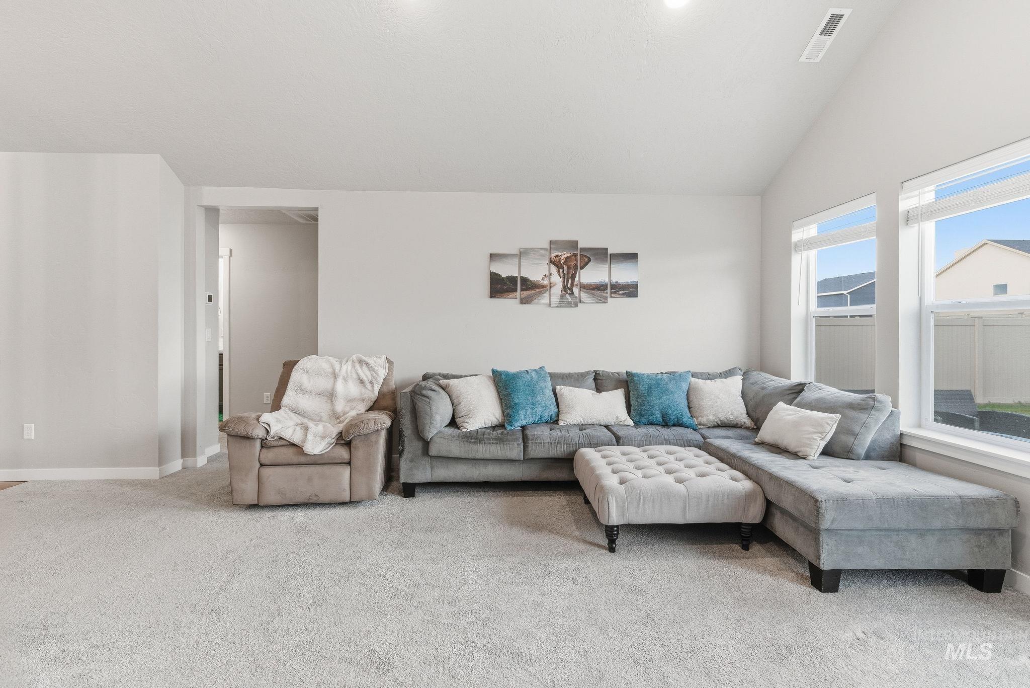 Living room with vaulted ceiling and light colored carpet