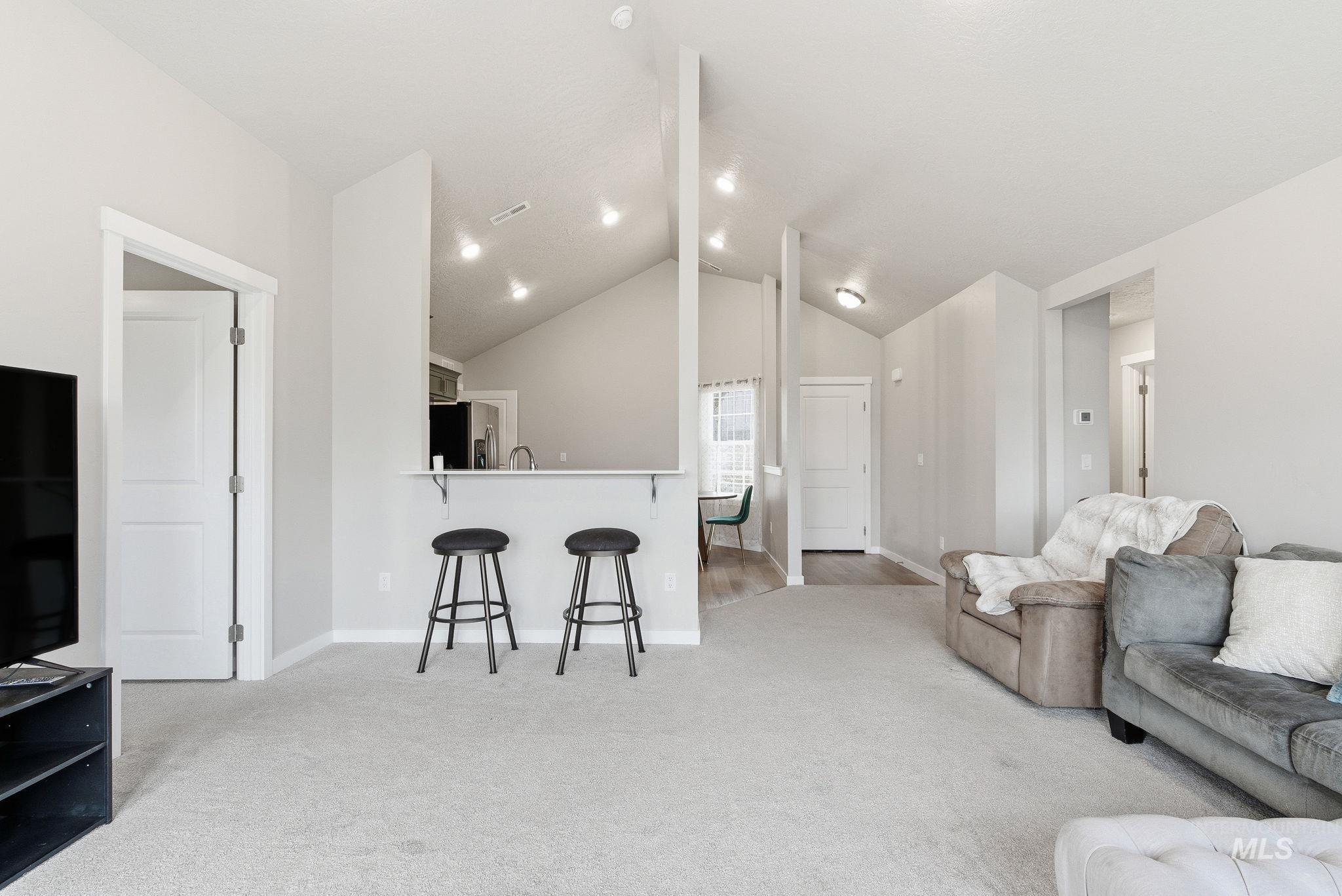 Living area featuring light colored carpet and lofted ceiling