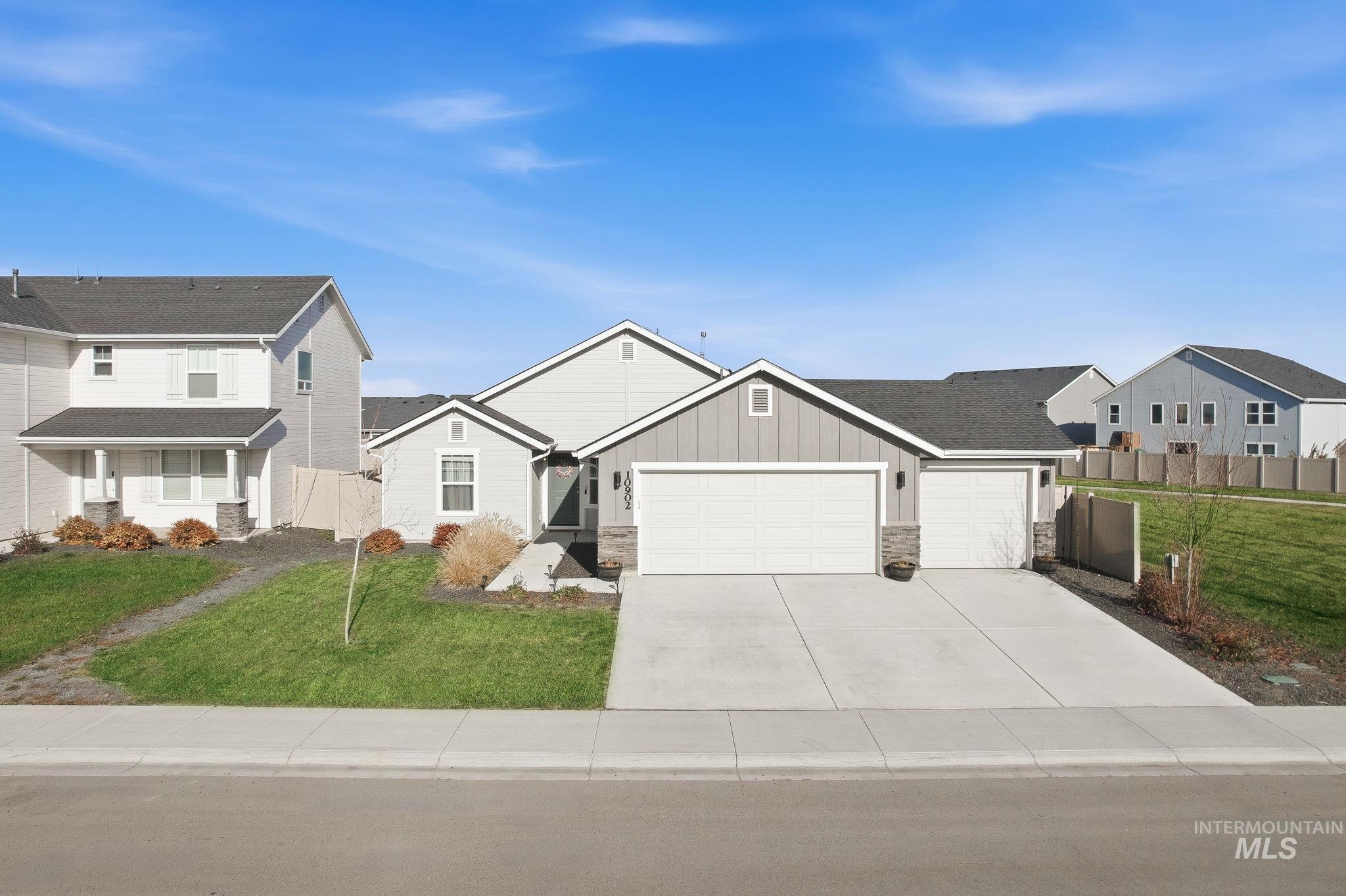 View of front of house with board and batten siding, stone siding, concrete driveway, a garage, and covered porch