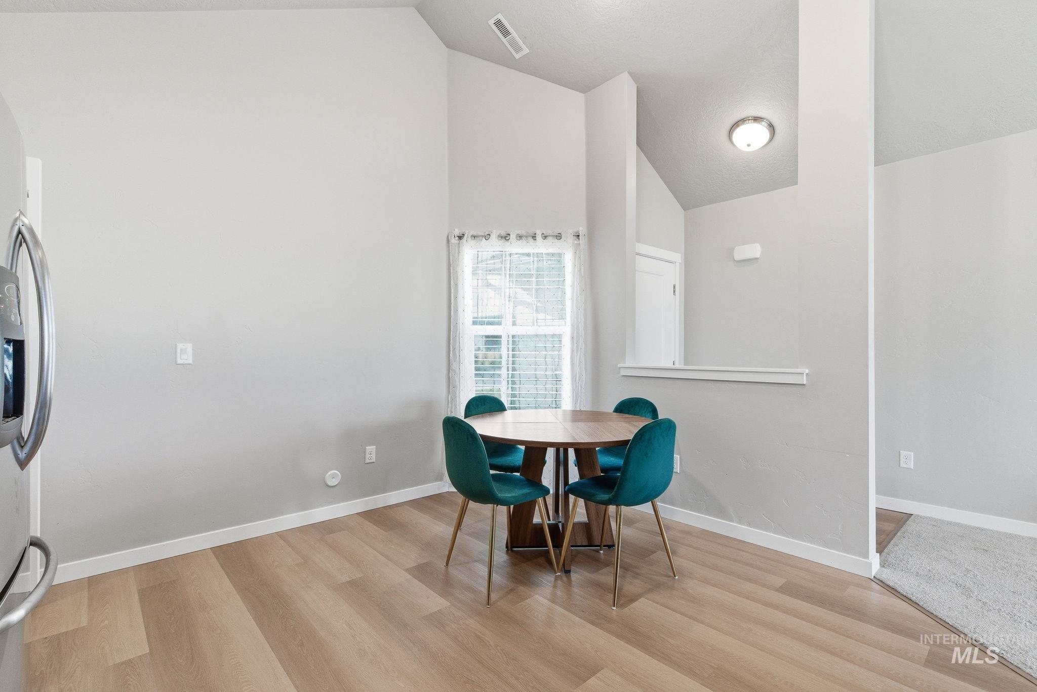 Dining area featuring light wood-style floors and high vaulted ceiling