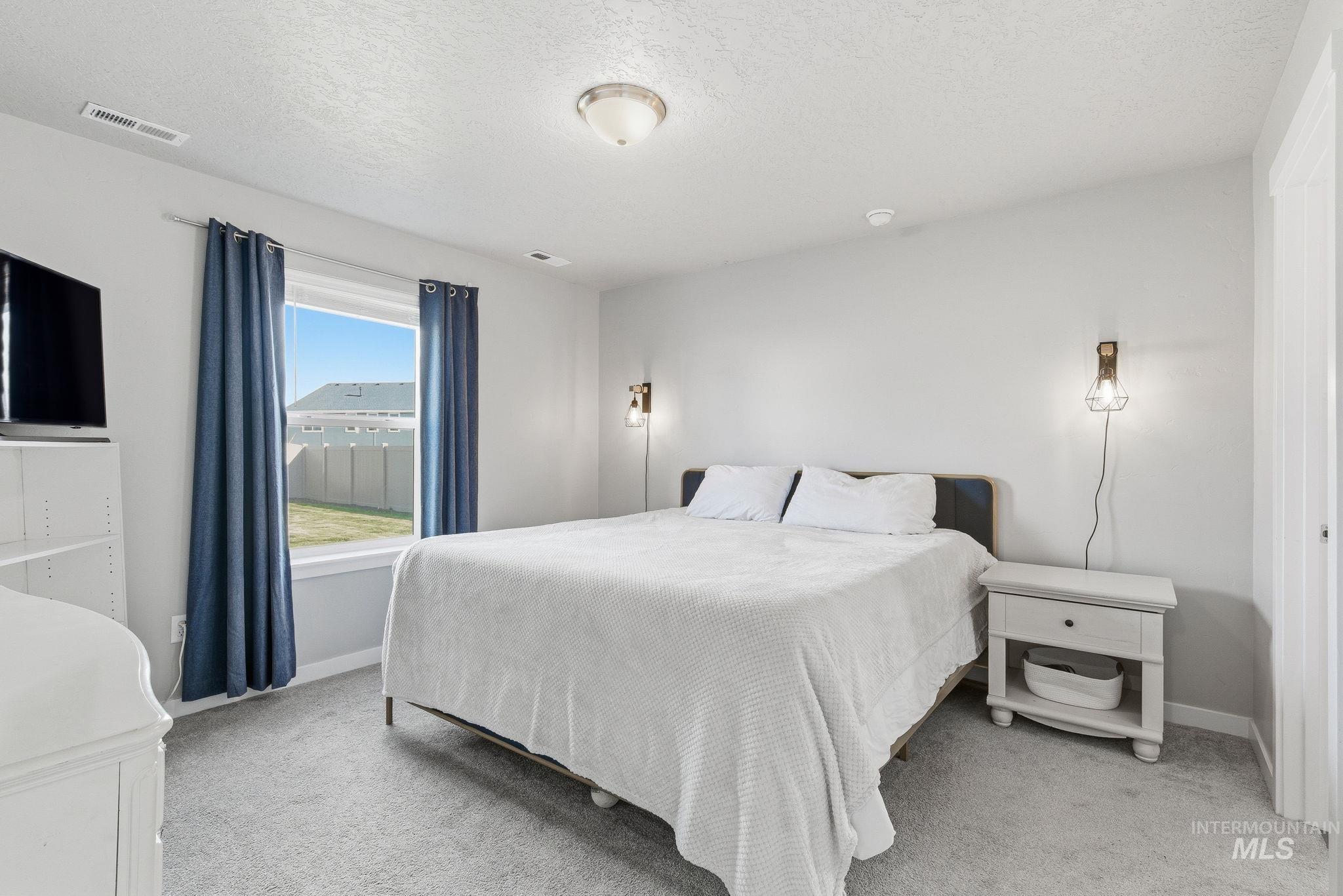 Bedroom with light colored carpet and a textured ceiling