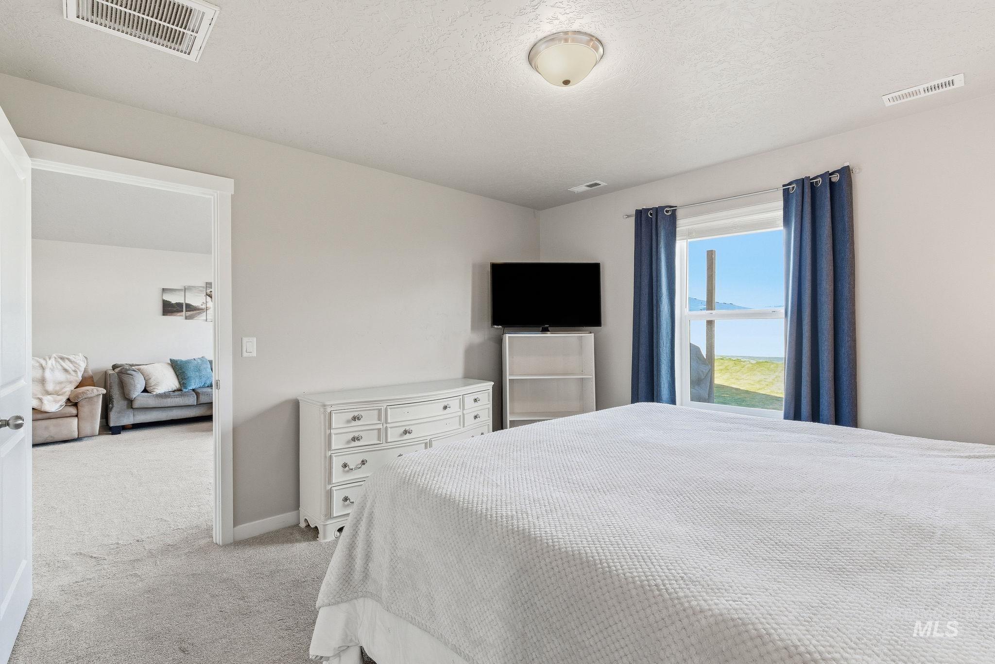 Bedroom featuring light colored carpet and a textured ceiling