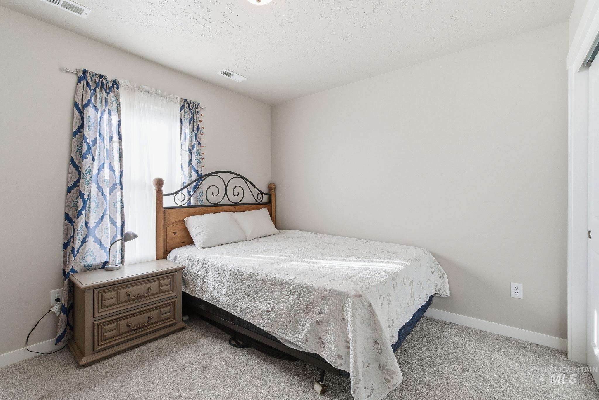 Bedroom with light carpet and a textured ceiling