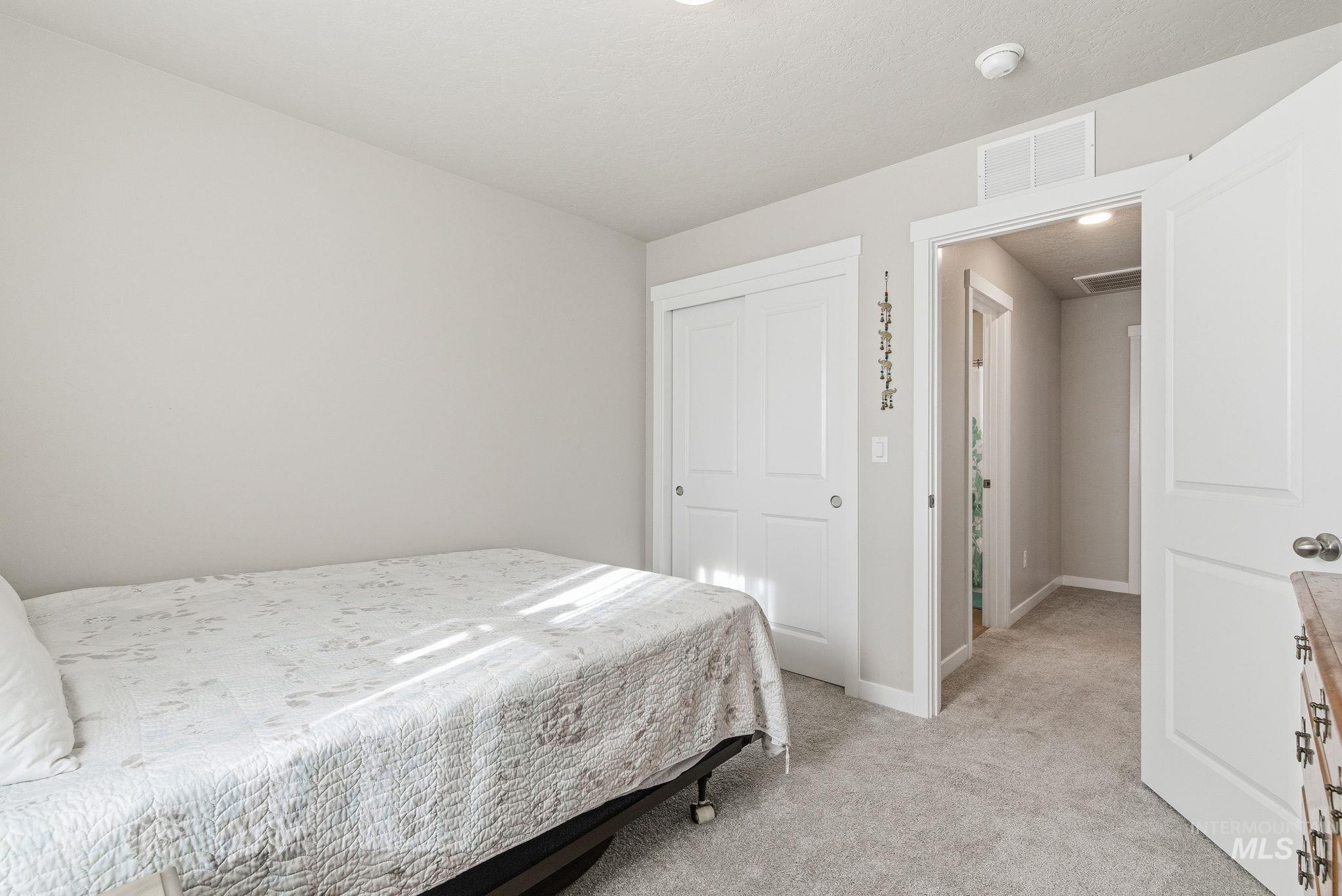 Bedroom with light colored carpet and a closet