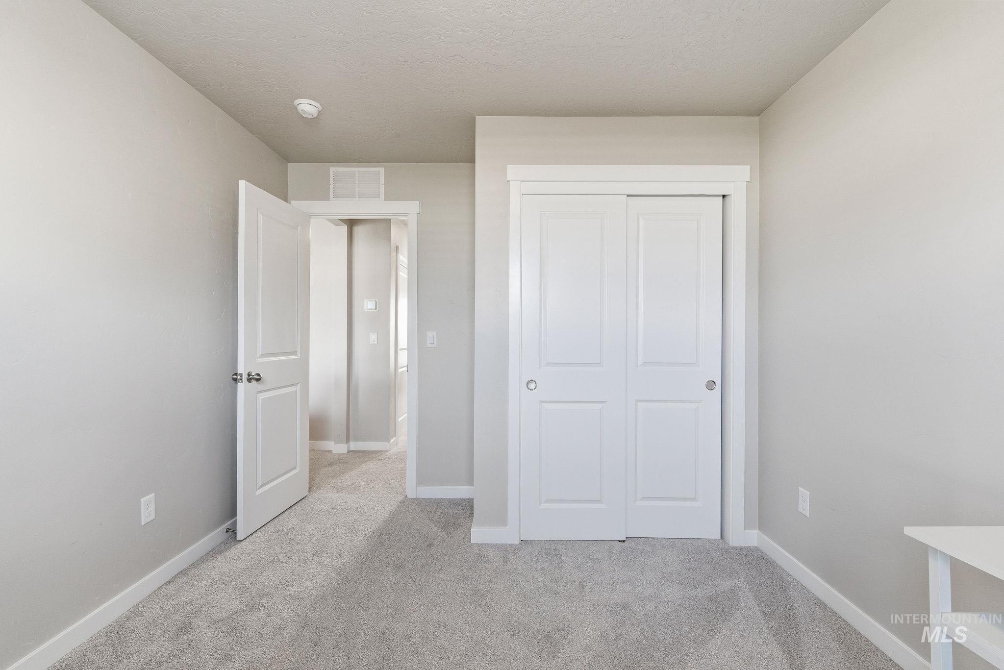 Unfurnished bedroom featuring light colored carpet, a closet, and a textured ceiling
