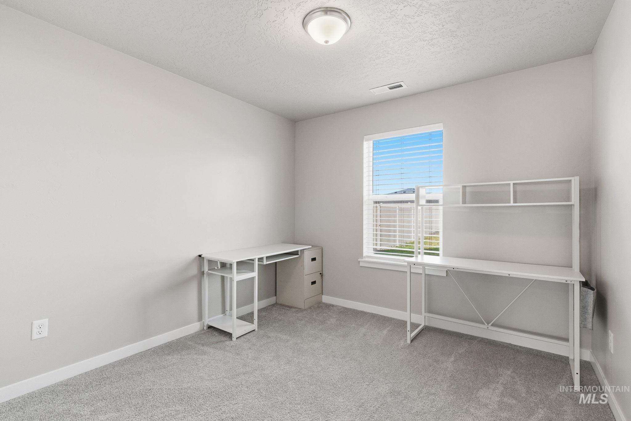 Unfurnished office featuring light carpet and a textured ceiling