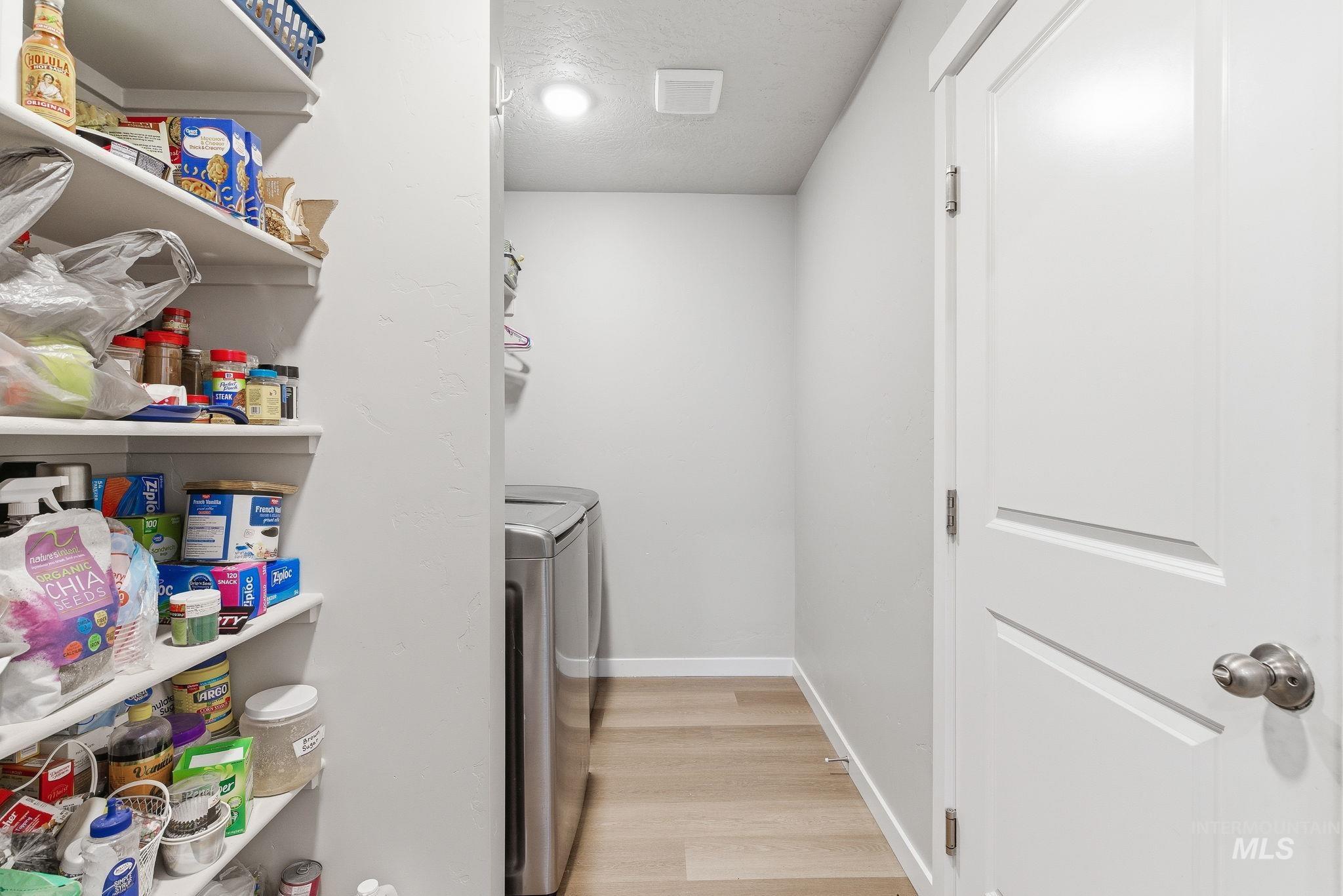 Laundry area featuring light wood-type flooring, washing machine and dryer, and a textured ceiling
