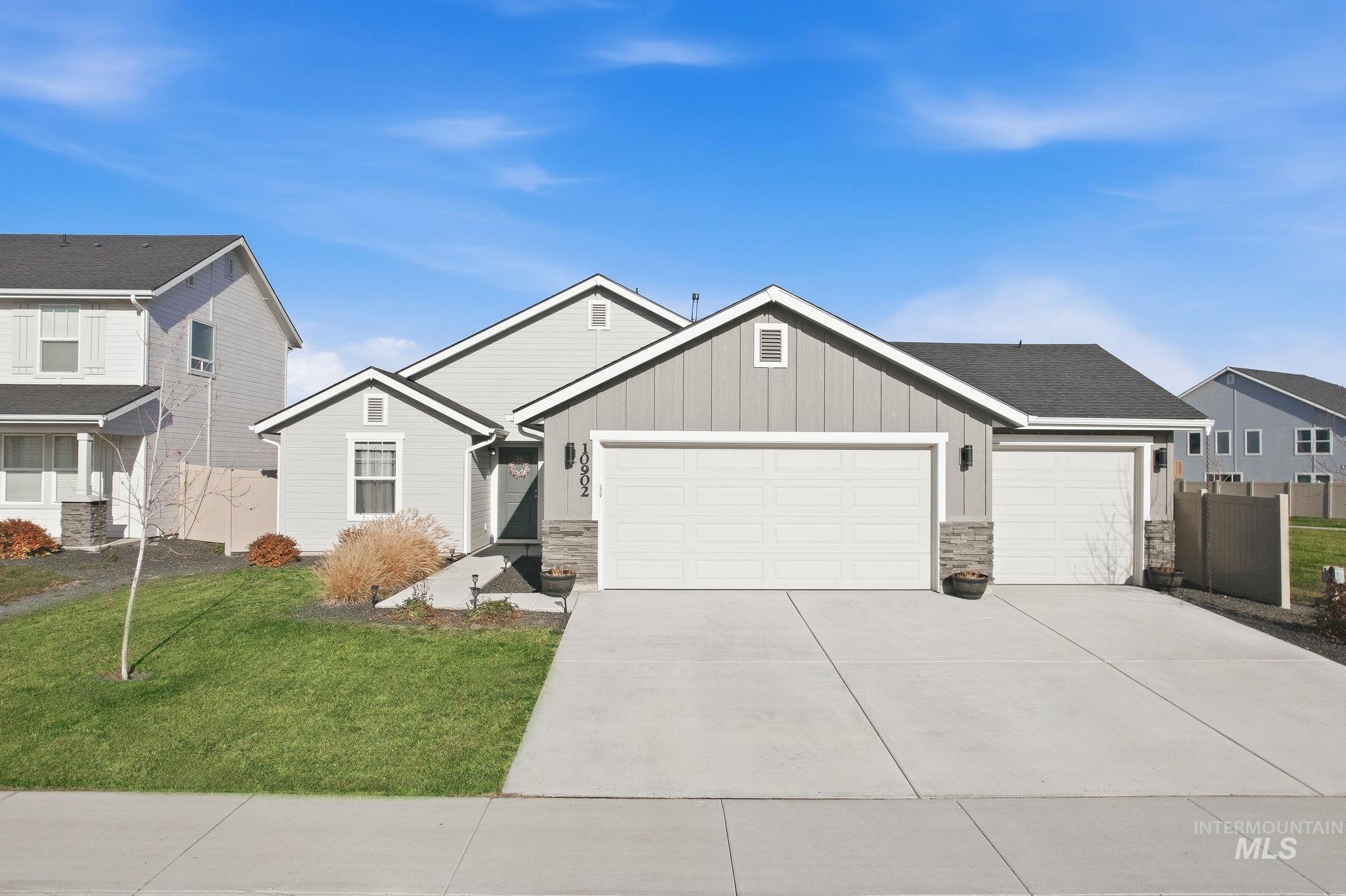 View of front of home with stone siding, board and batten siding, an attached garage, and driveway