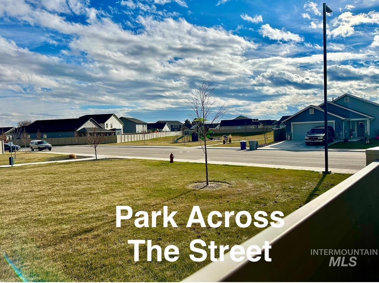 View of yard featuring a residential view, concrete driveway, and a garage