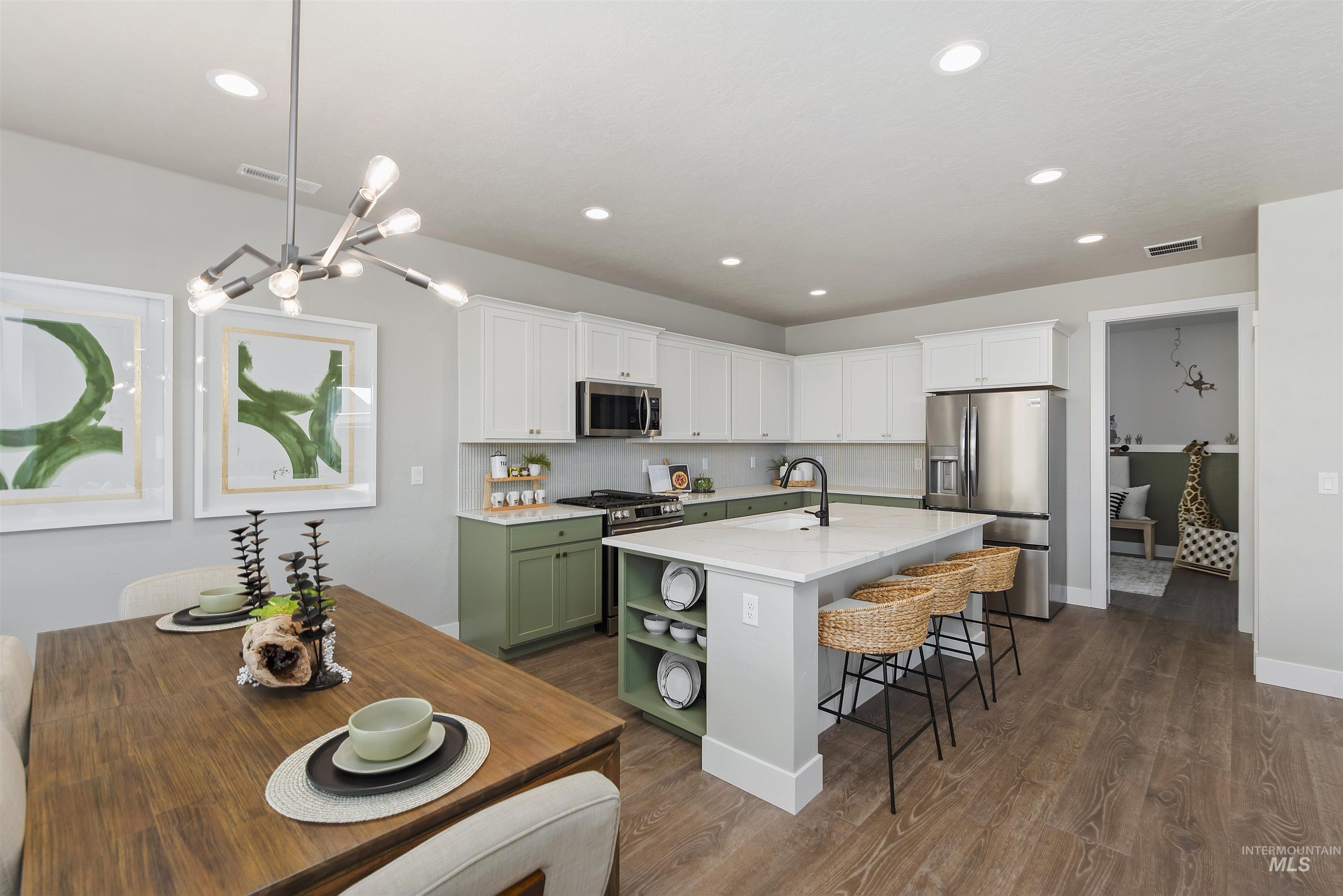 Kitchen with appliances with stainless steel finishes, white cabinets, green cabinets, tasteful backsplash, and recessed lighting