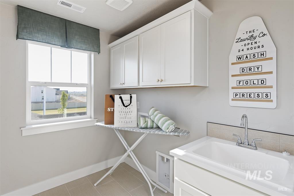 Washroom featuring cabinet space, light tile patterned floors, and hookup for a washing machine