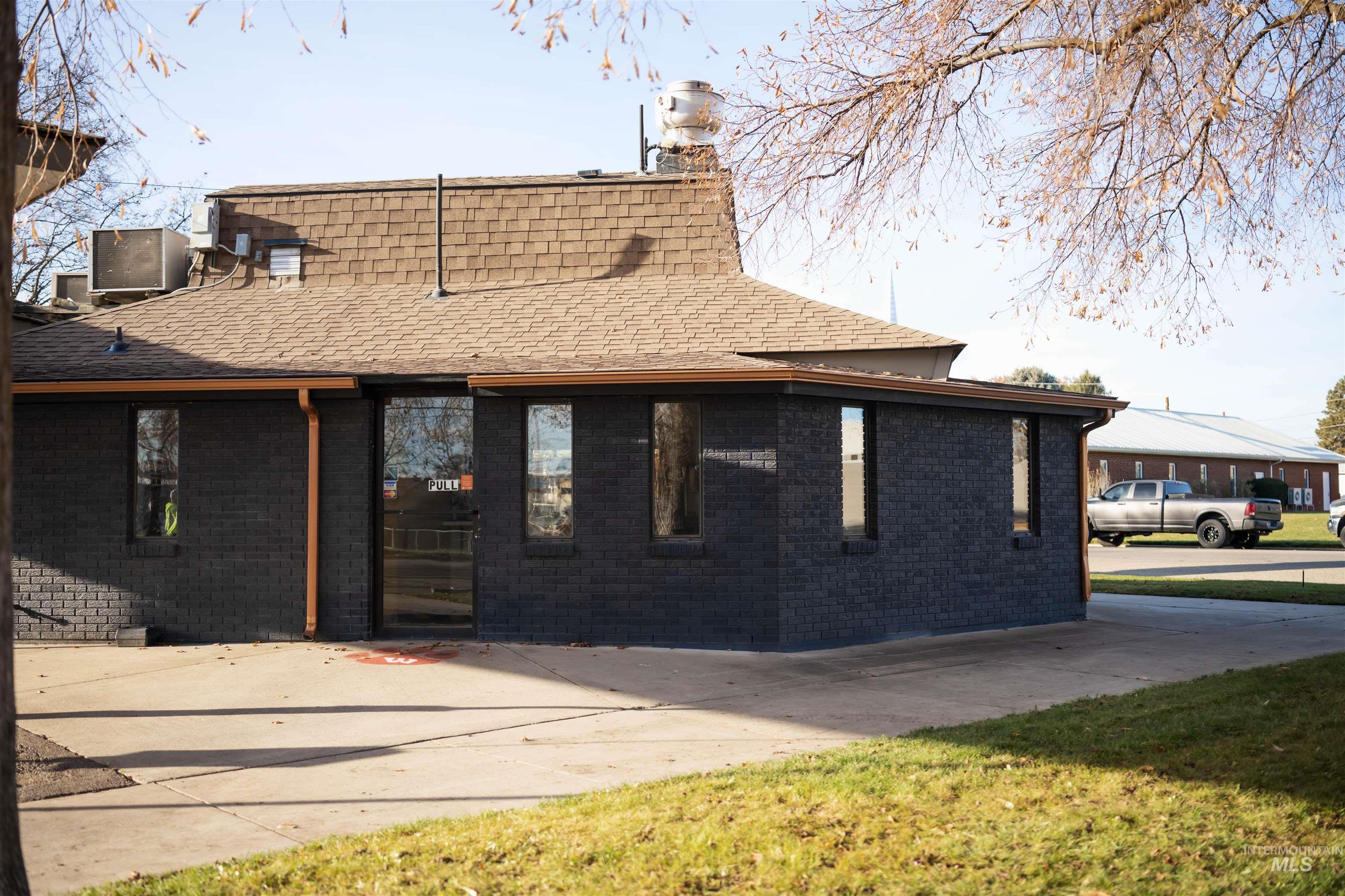 View of front of property with brick siding, roof with shingles, and a chimney