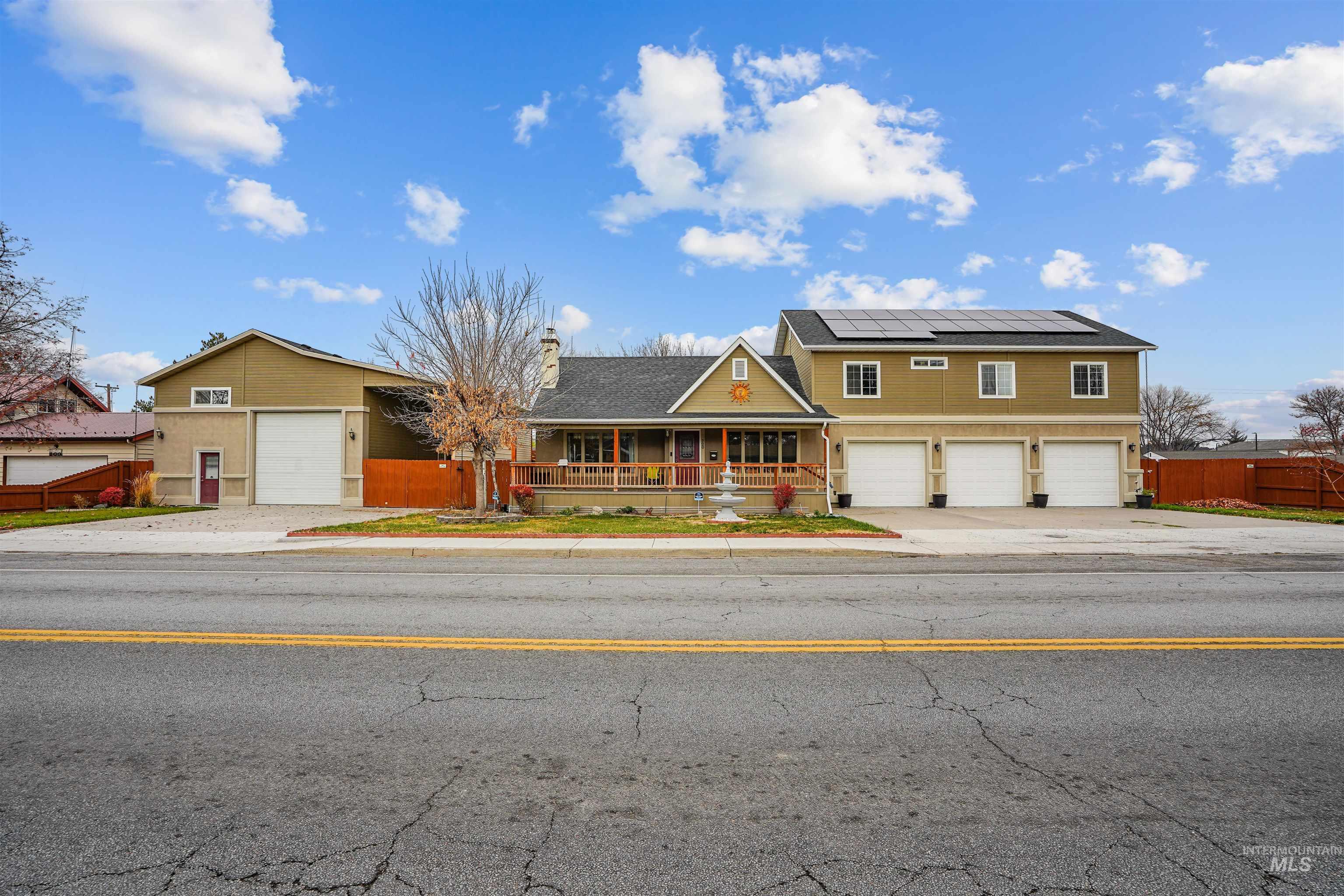 View of front of property featuring a porch, a garage, a chimney, and roof mounted solar panels