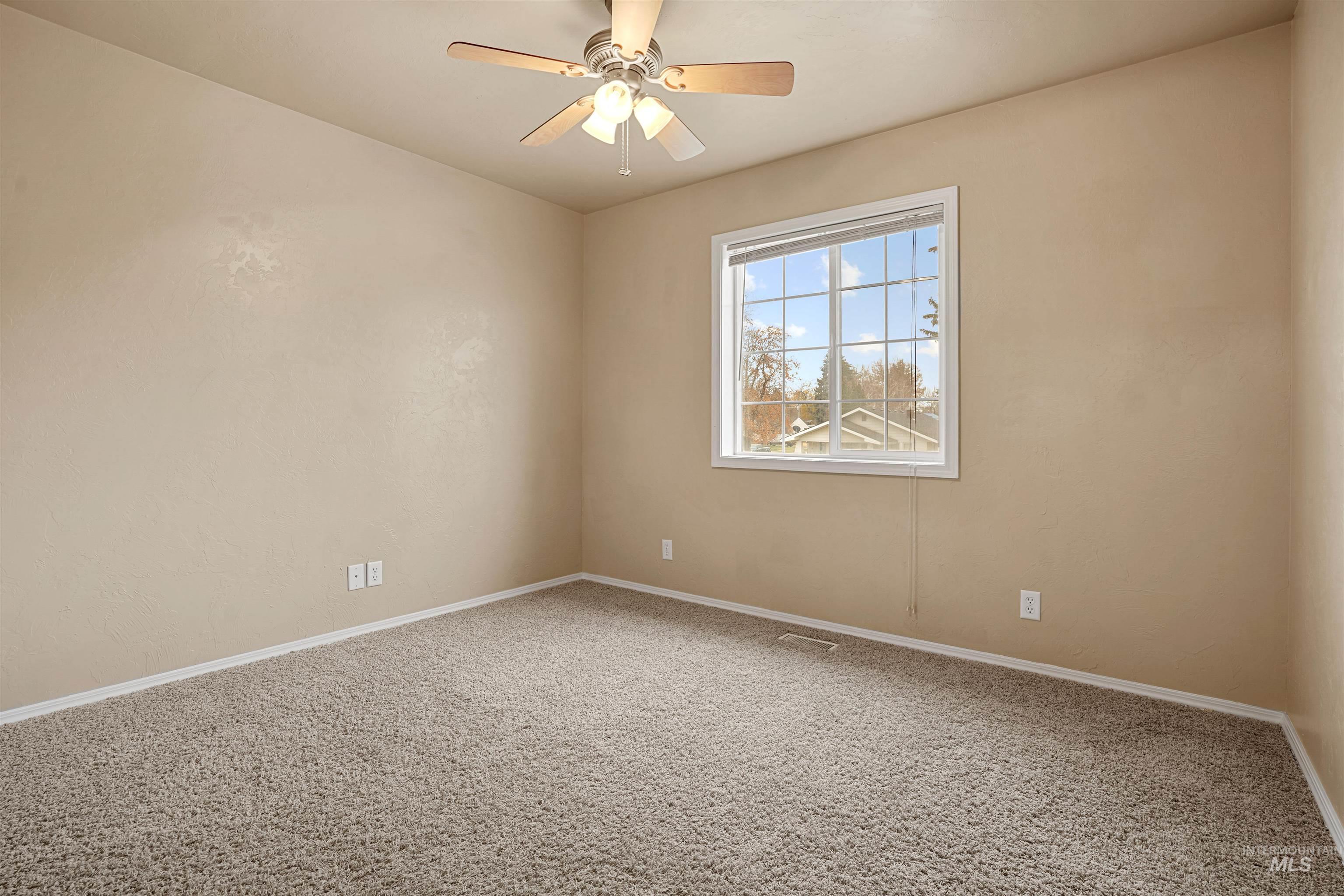 Carpeted spare room with baseboards and ceiling fan