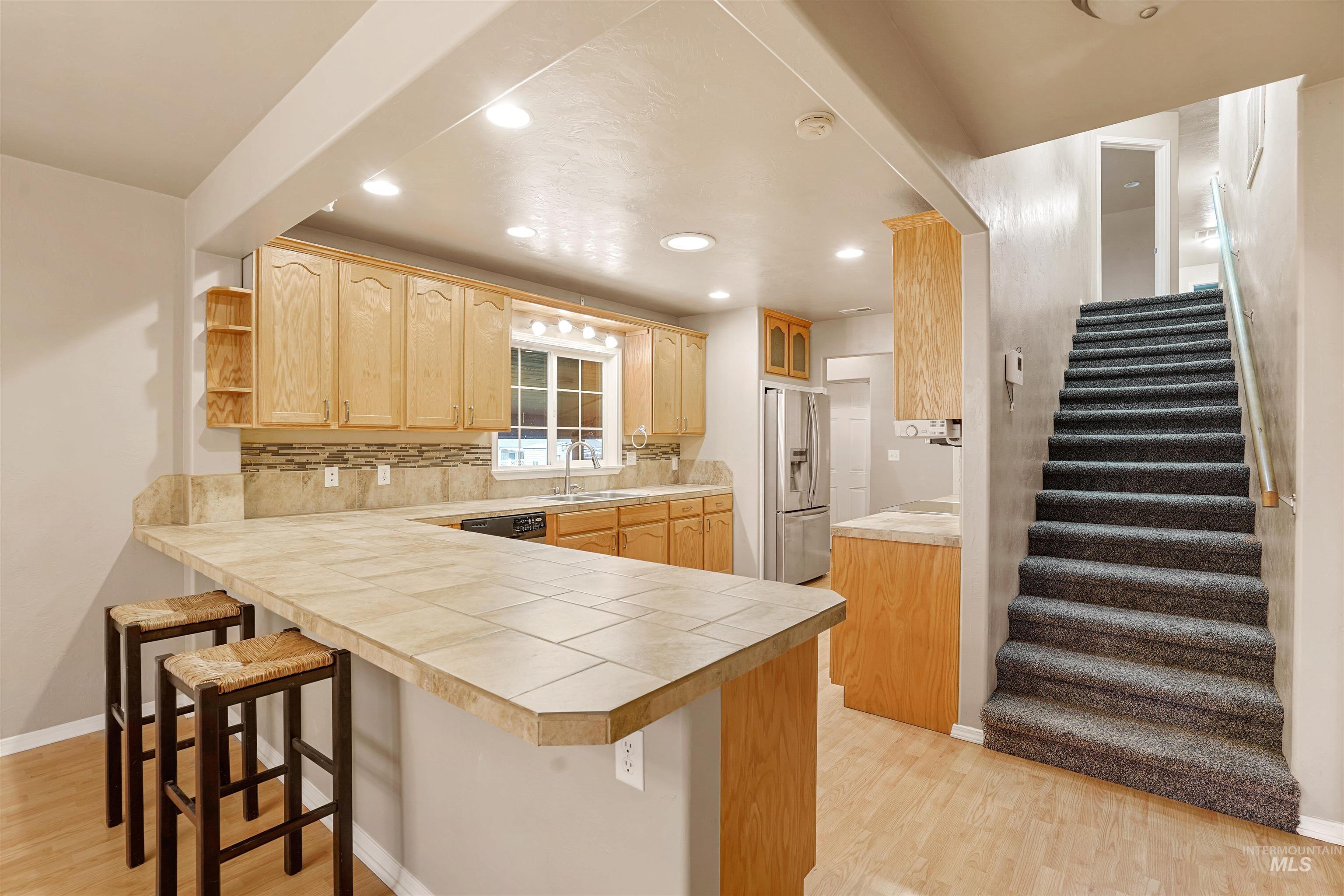 Kitchen featuring a kitchen breakfast bar, a peninsula, open shelves, light wood-type flooring, and recessed lighting