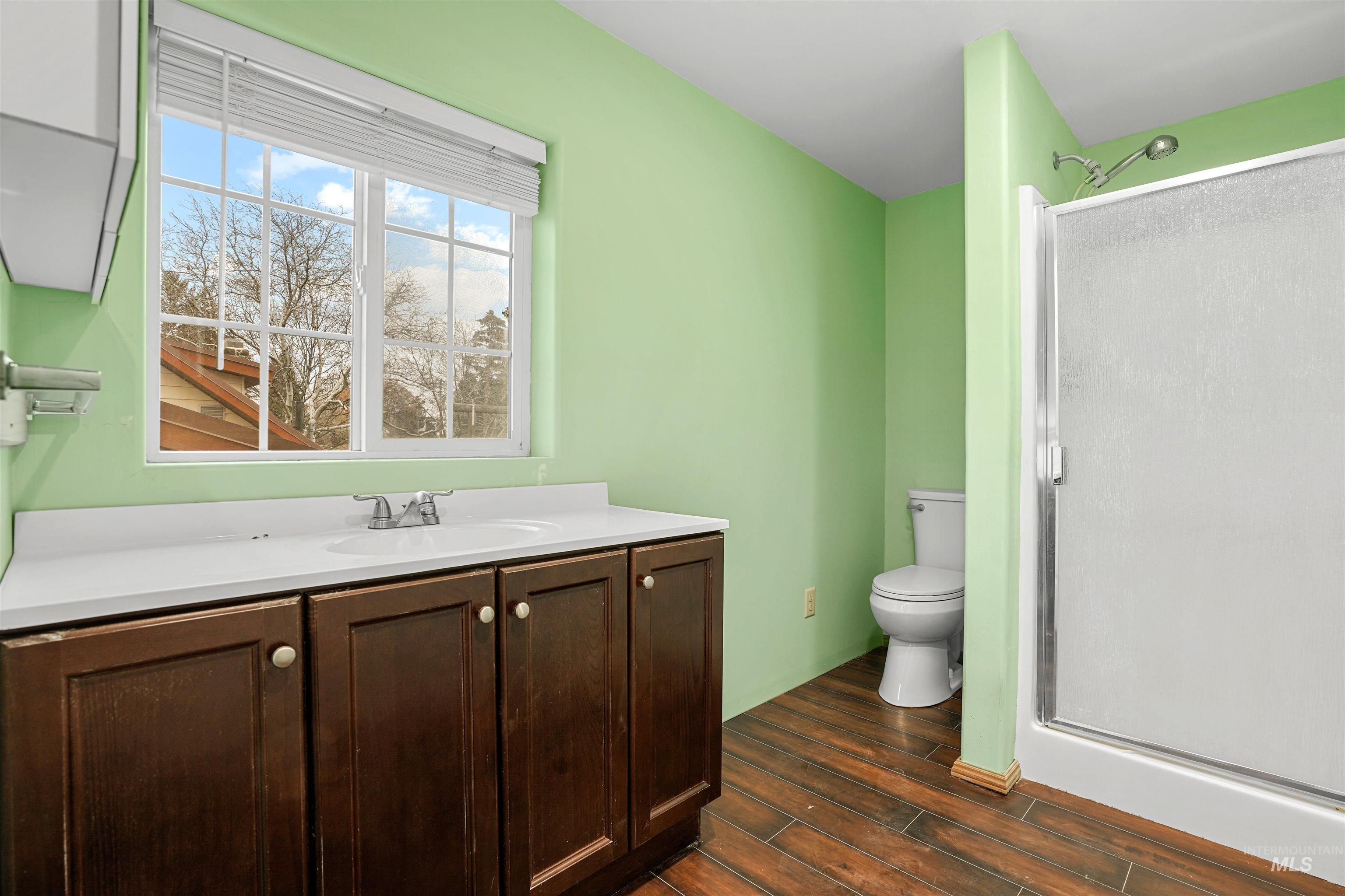 Bathroom with vanity, a shower stall, and wood tiled floors