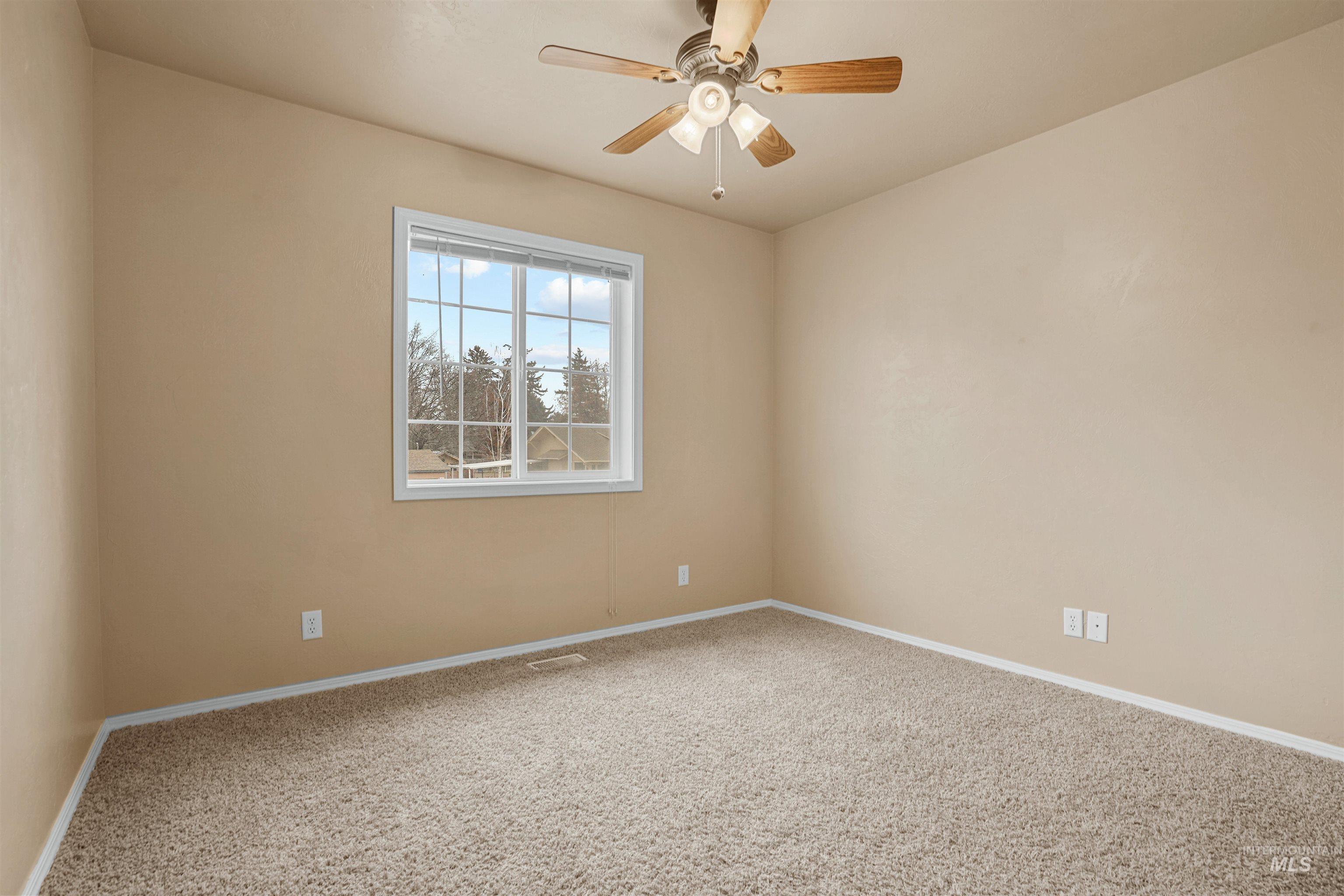 Carpeted empty room featuring ceiling fan and baseboards