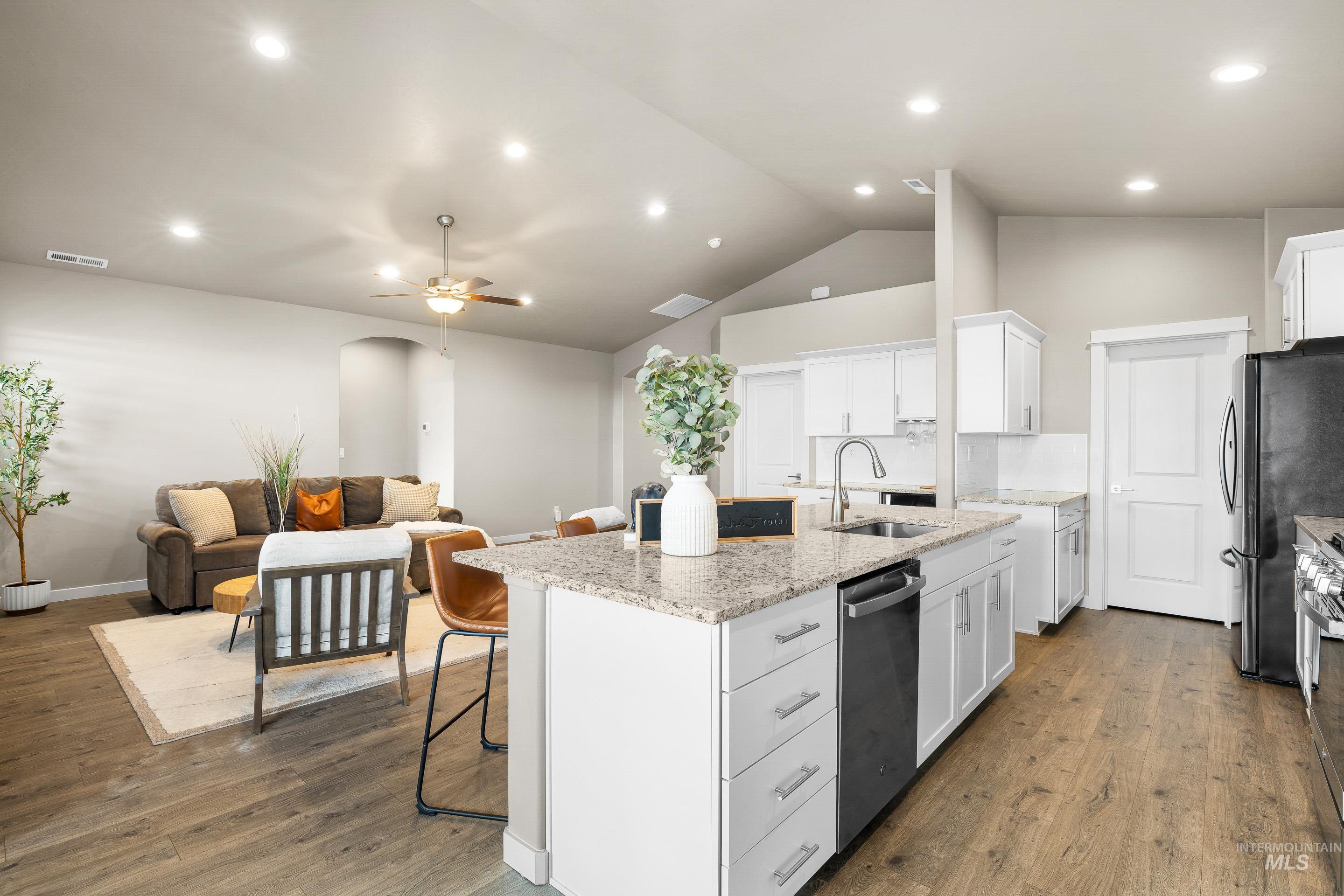 Kitchen with white cabinets, a kitchen bar, dark wood-style floors, a kitchen island with sink, and recessed lighting