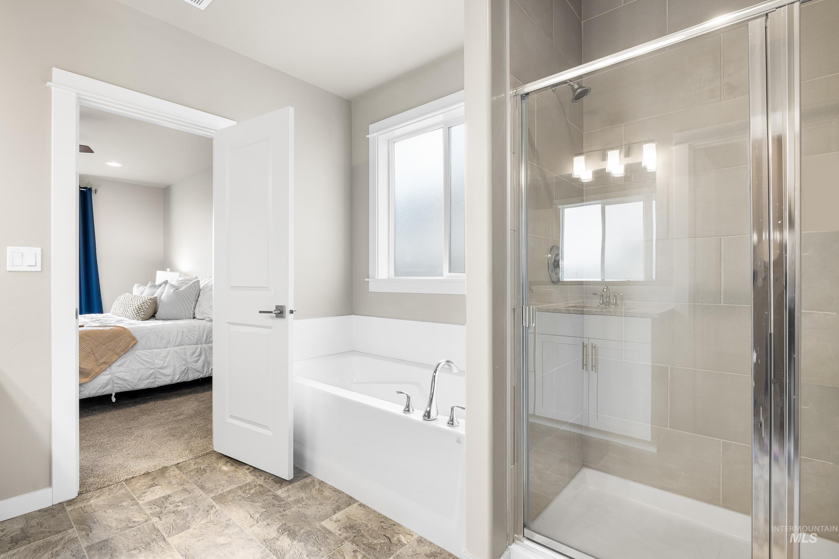 Ensuite bathroom featuring a garden tub and a stall shower