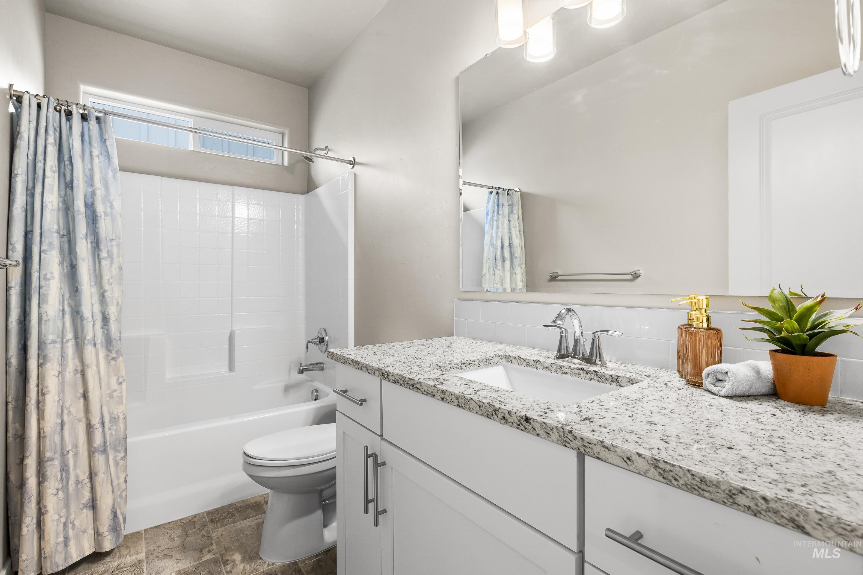 Full bathroom featuring vanity, shower / tub combo, and stone finish floors