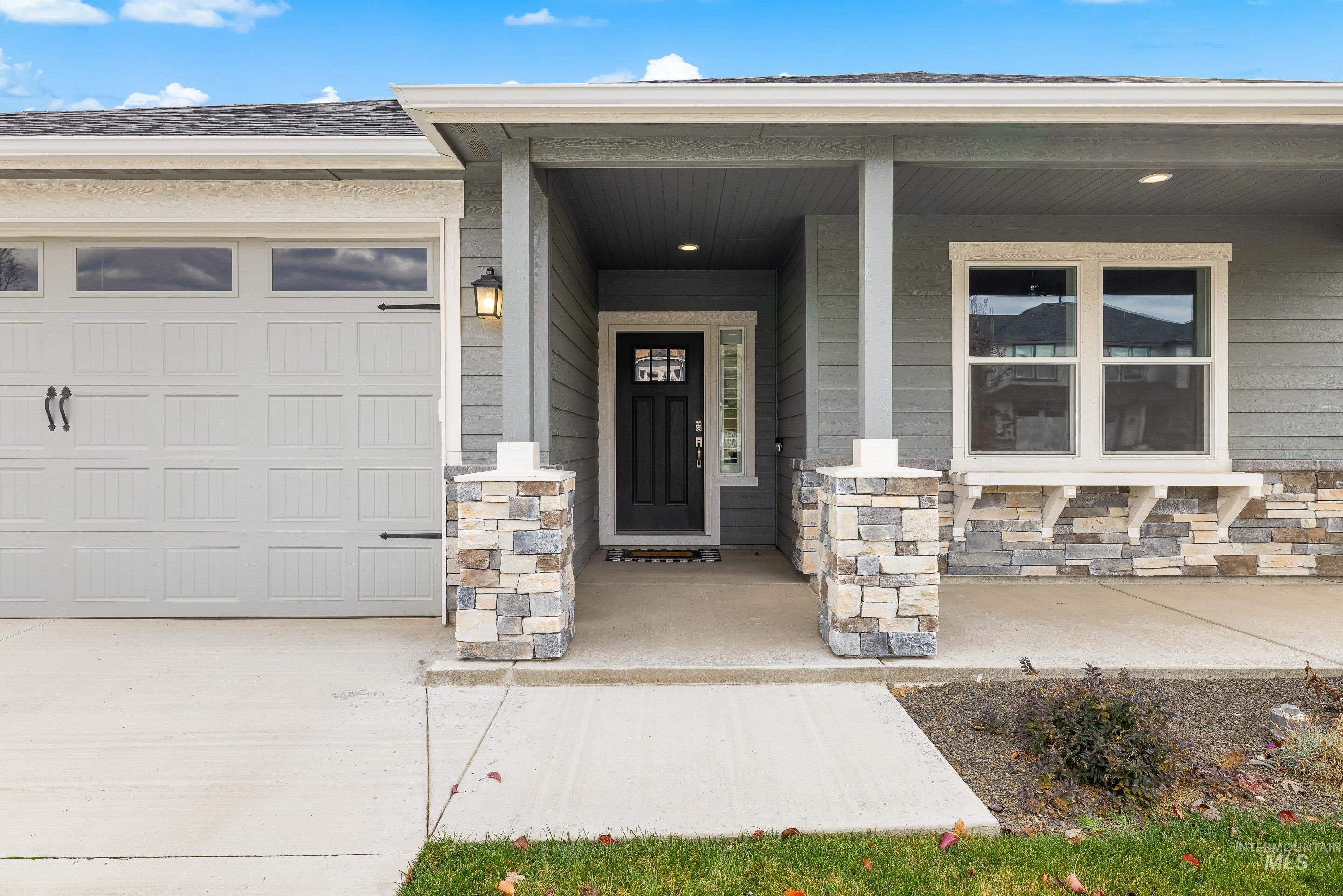 Property entrance with a porch, stone siding, and a garage