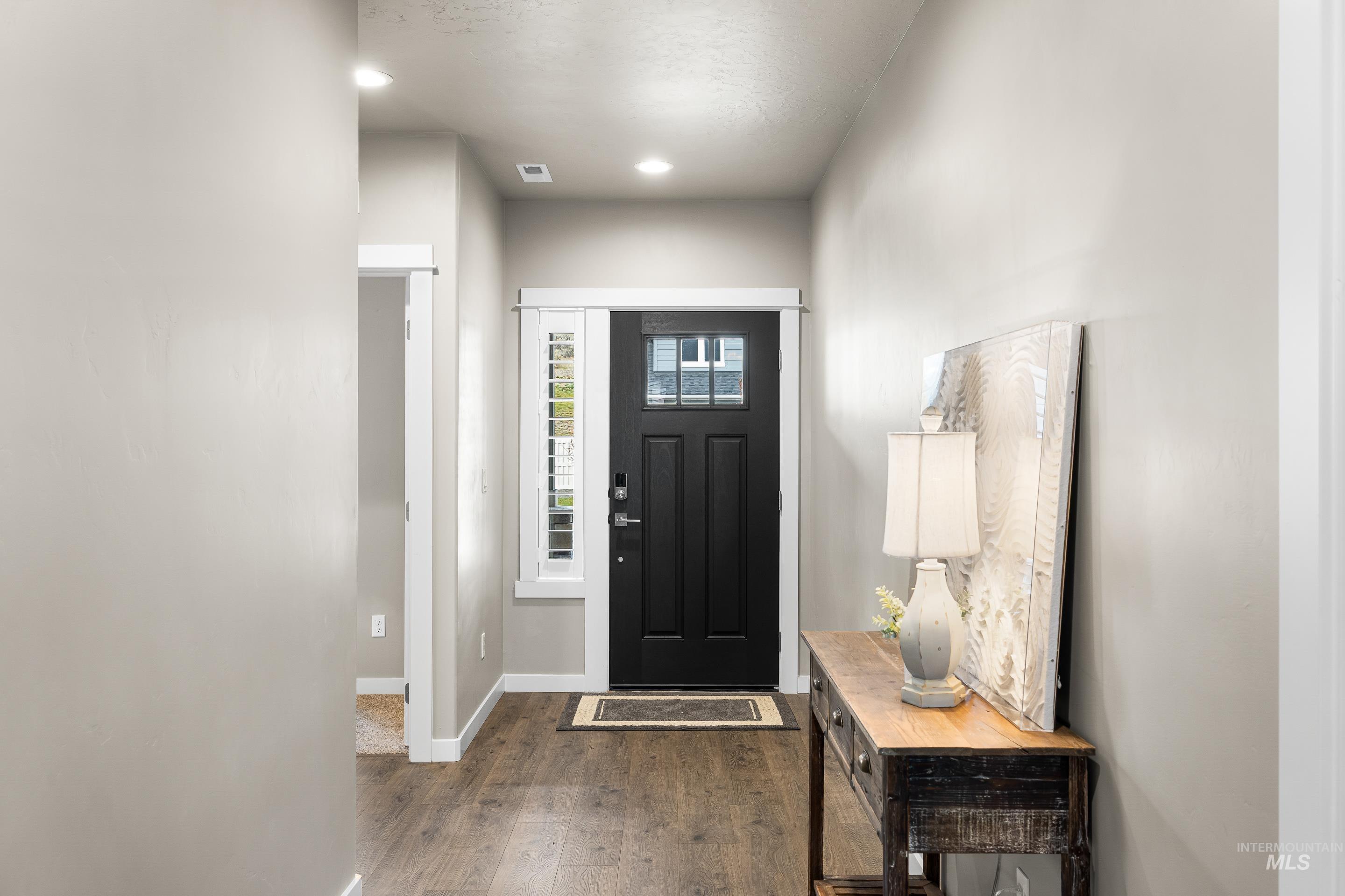 Foyer with dark wood-type flooring and baseboards