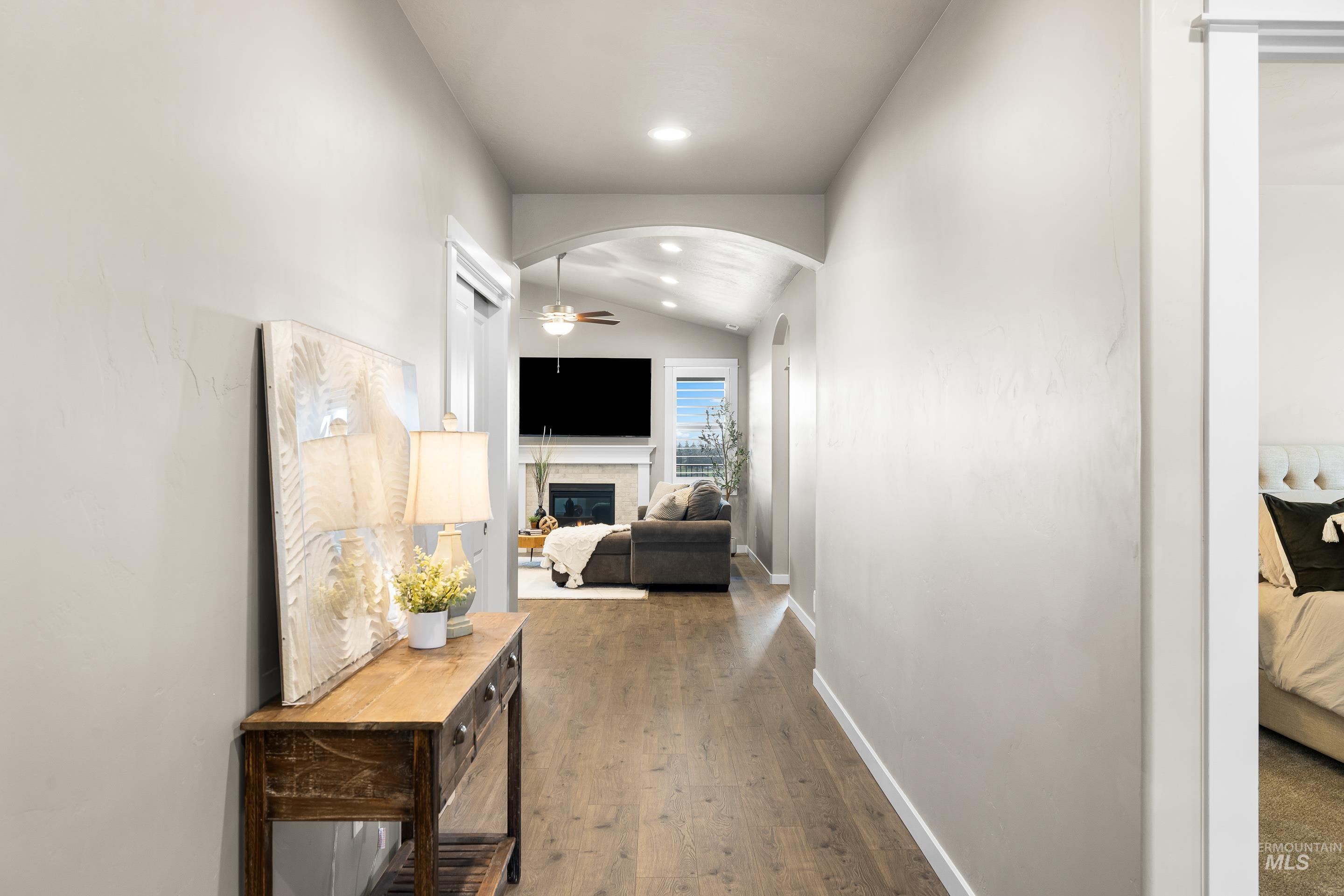 Hallway featuring arched walkways, lofted ceiling, dark wood-style flooring, and recessed lighting