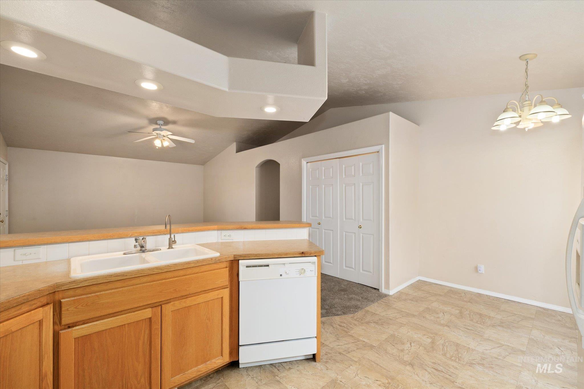 Kitchen with white appliances, light countertops, a chandelier, and decorative light fixtures