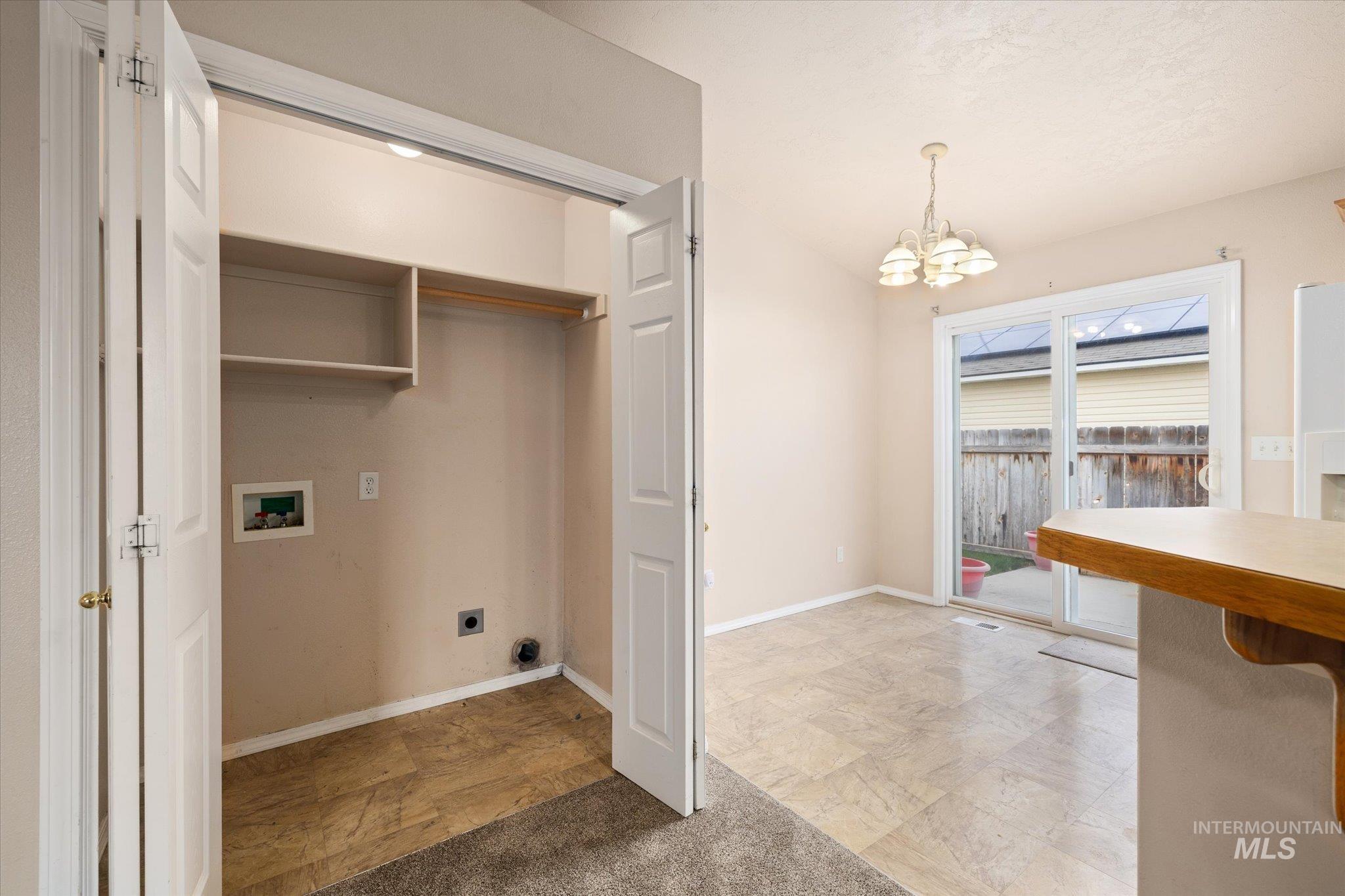 Washroom featuring a chandelier, washer hookup, electric dryer hookup, and light colored carpet
