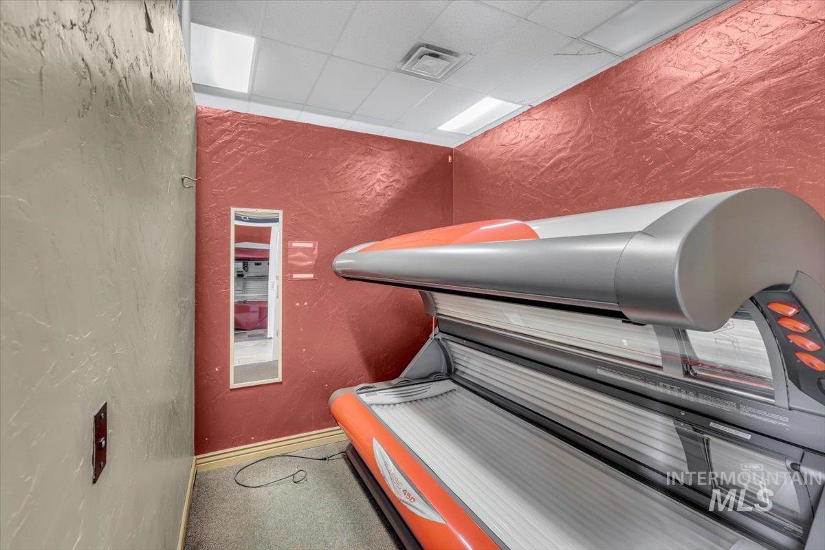 Misc room featuring a textured wall, a tanning bed, and a paneled ceiling