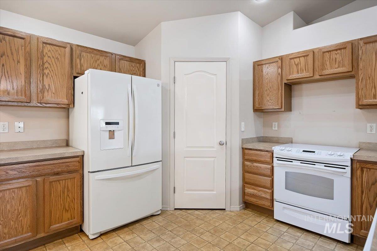 Kitchen featuring white appliances, light countertops, and brown cabinets