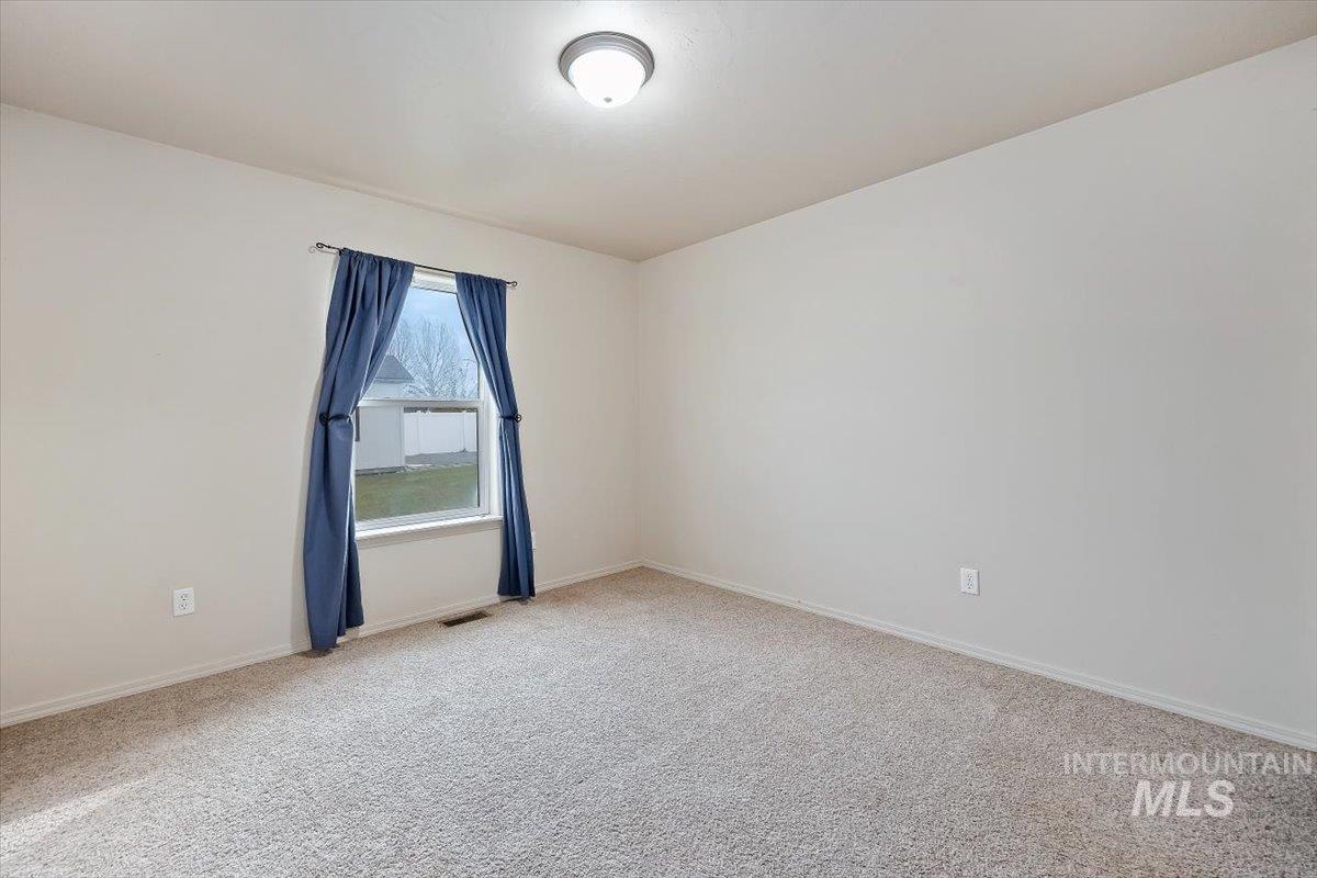 Empty room with light colored carpet and baseboards