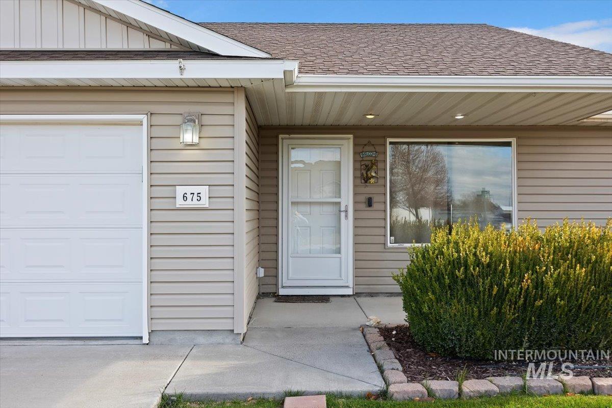 Property entrance with roof with shingles and a garage