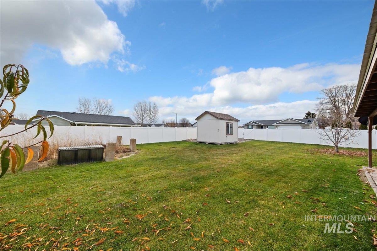 Fenced backyard featuring a storage shed