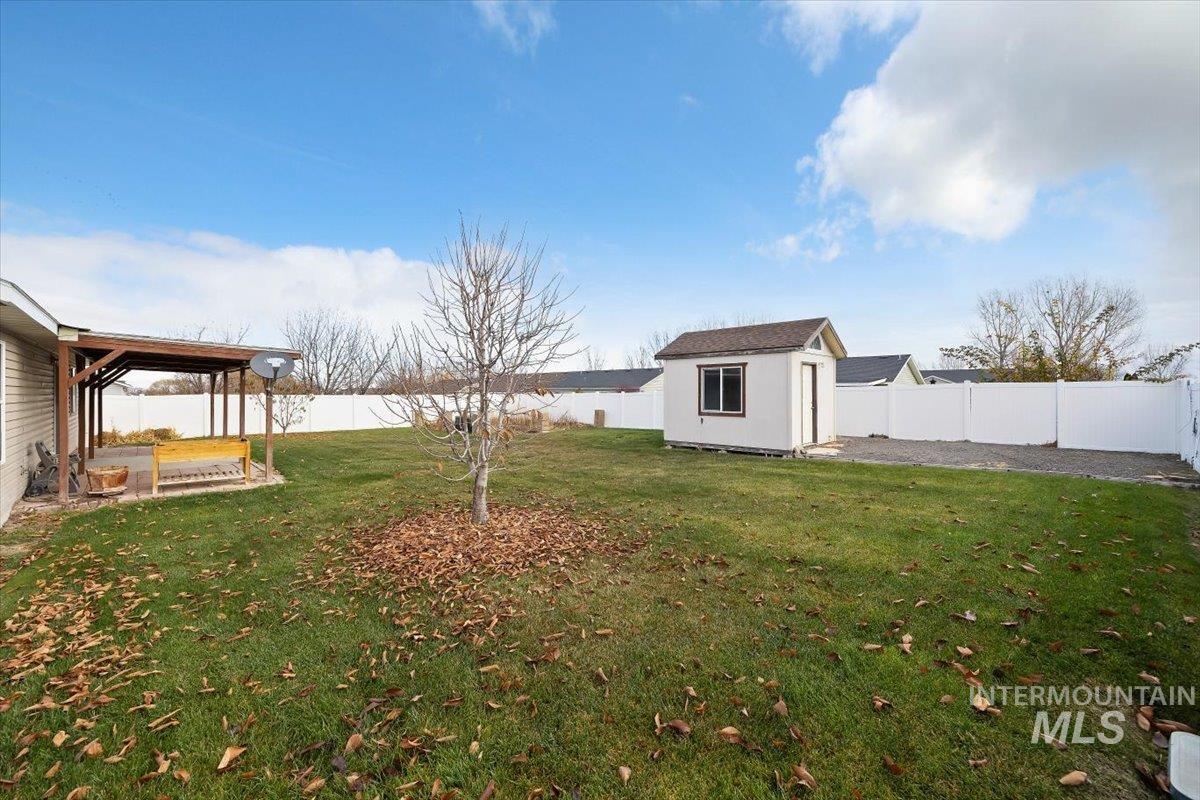 Fenced backyard with a storage unit and a patio area
