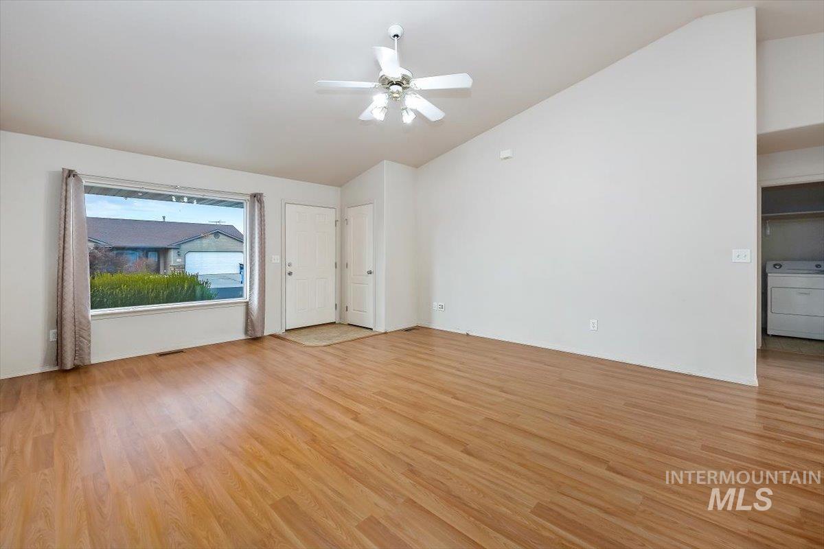 Unfurnished living room featuring lofted ceiling, washer / clothes dryer, light wood finished floors, and ceiling fan