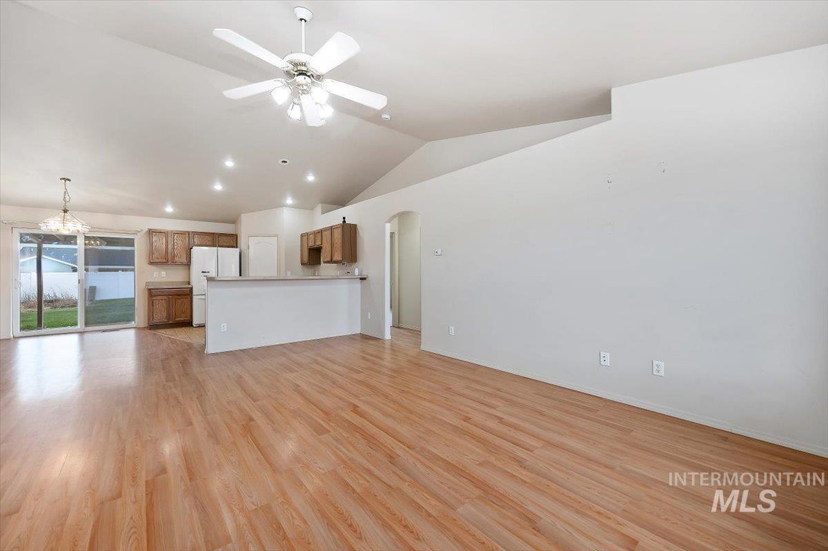 Unfurnished living room featuring lofted ceiling, light wood finished floors, arched walkways, recessed lighting, and ceiling fan