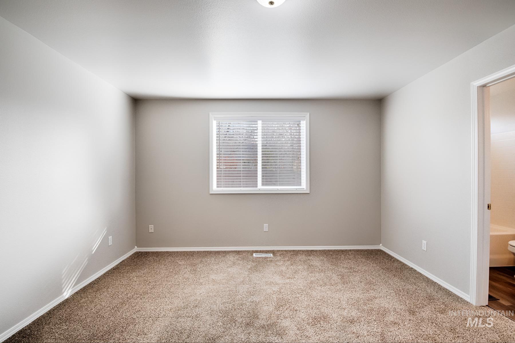 Empty room with light colored carpet and baseboards