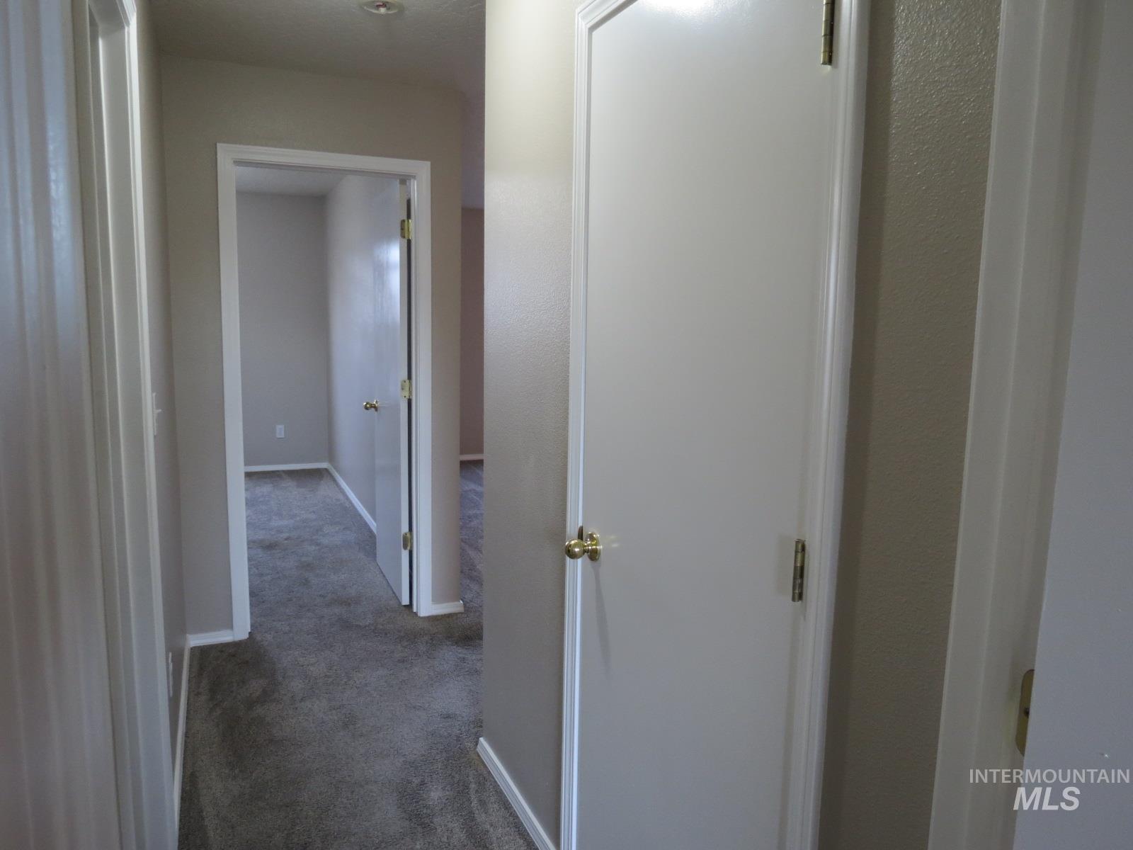 Corridor featuring dark carpet and baseboards