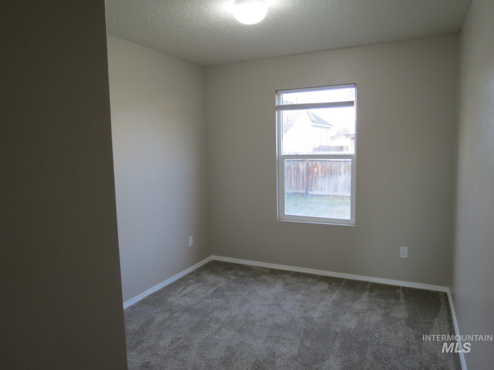 Unfurnished room featuring a textured ceiling and carpet floors