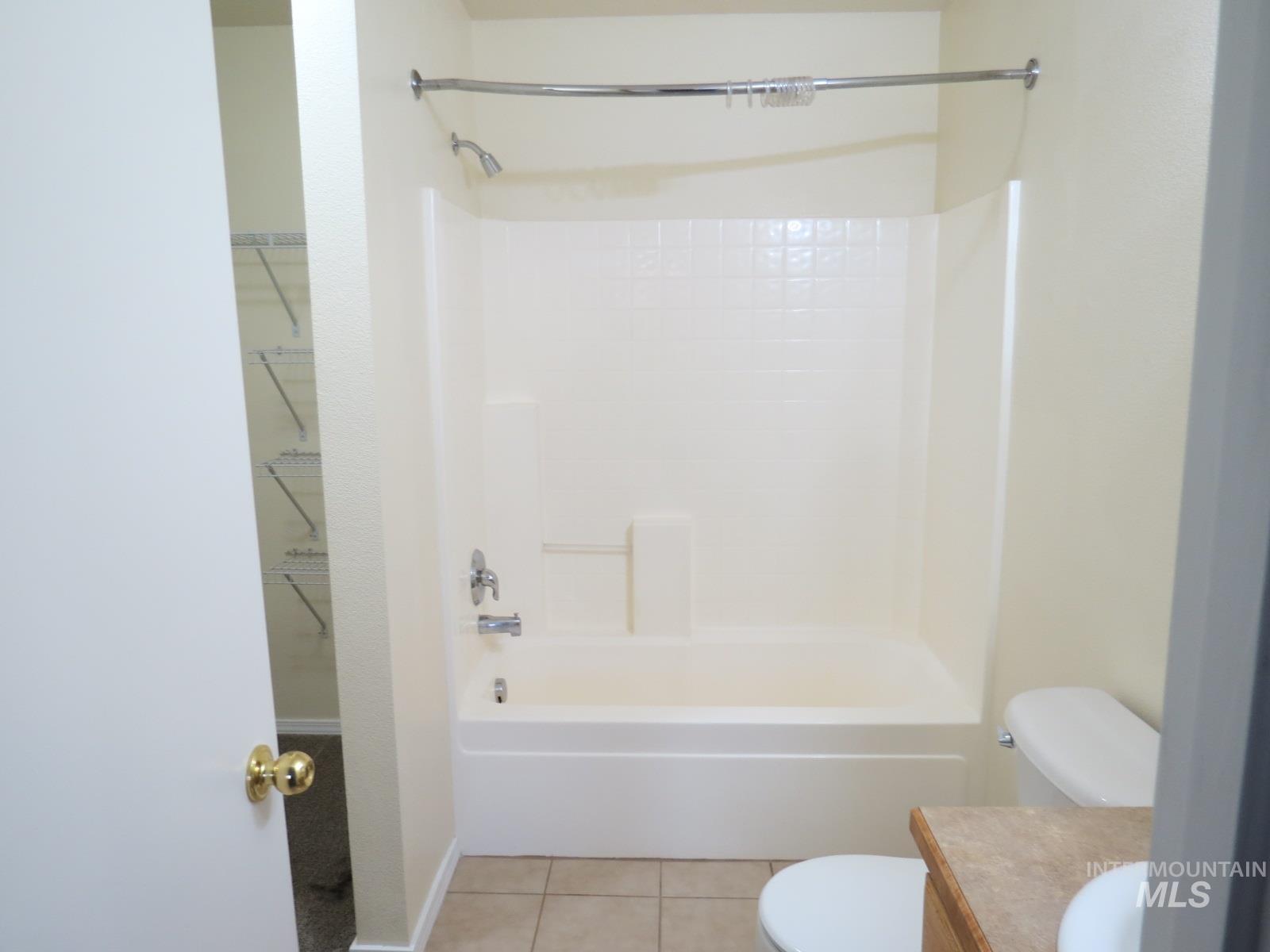 Bathroom with light tile patterned floors, vanity, shower / bath combination, and a spacious closet