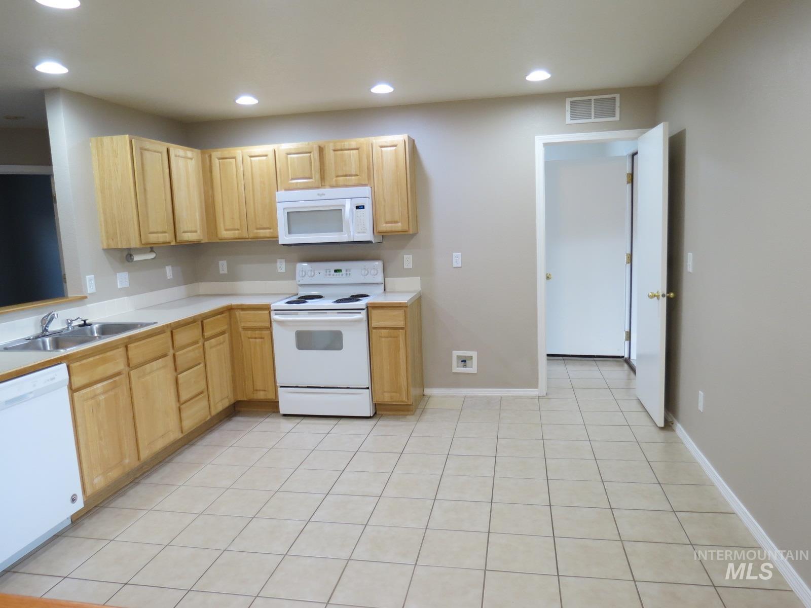 Kitchen with white appliances, light countertops, recessed lighting, light brown cabinets, and light tile patterned floors
