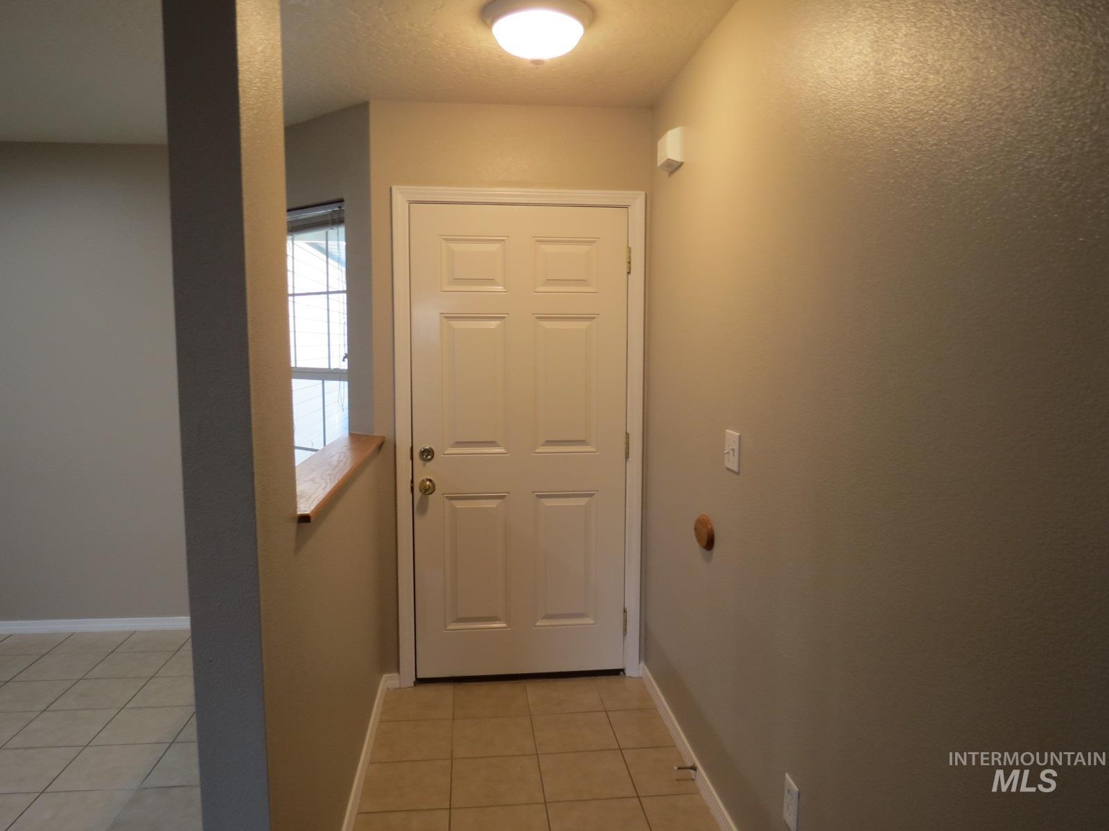 Doorway to outside featuring tile patterned flooring and a textured ceiling