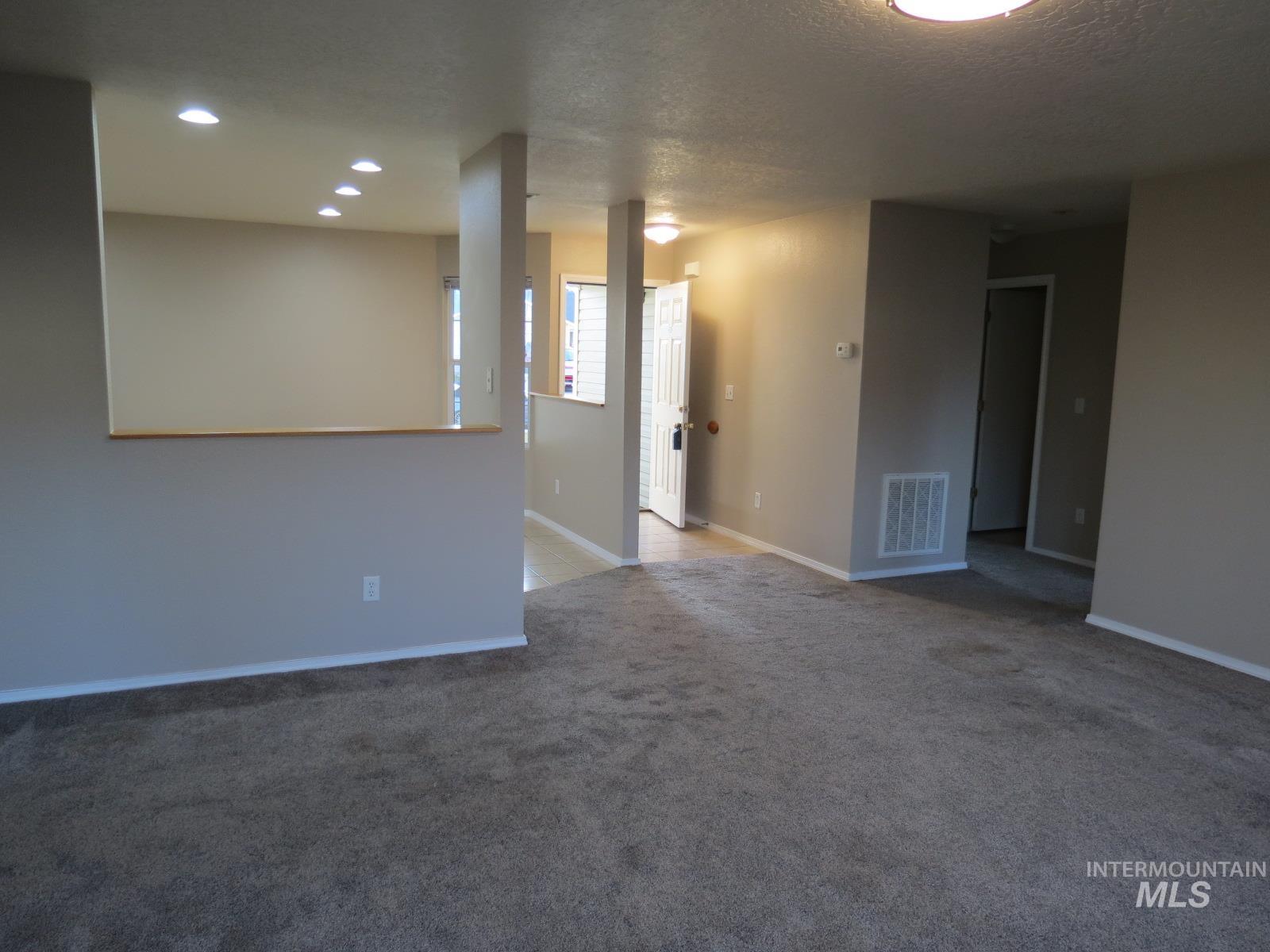 Carpeted spare room with a textured ceiling and recessed lighting