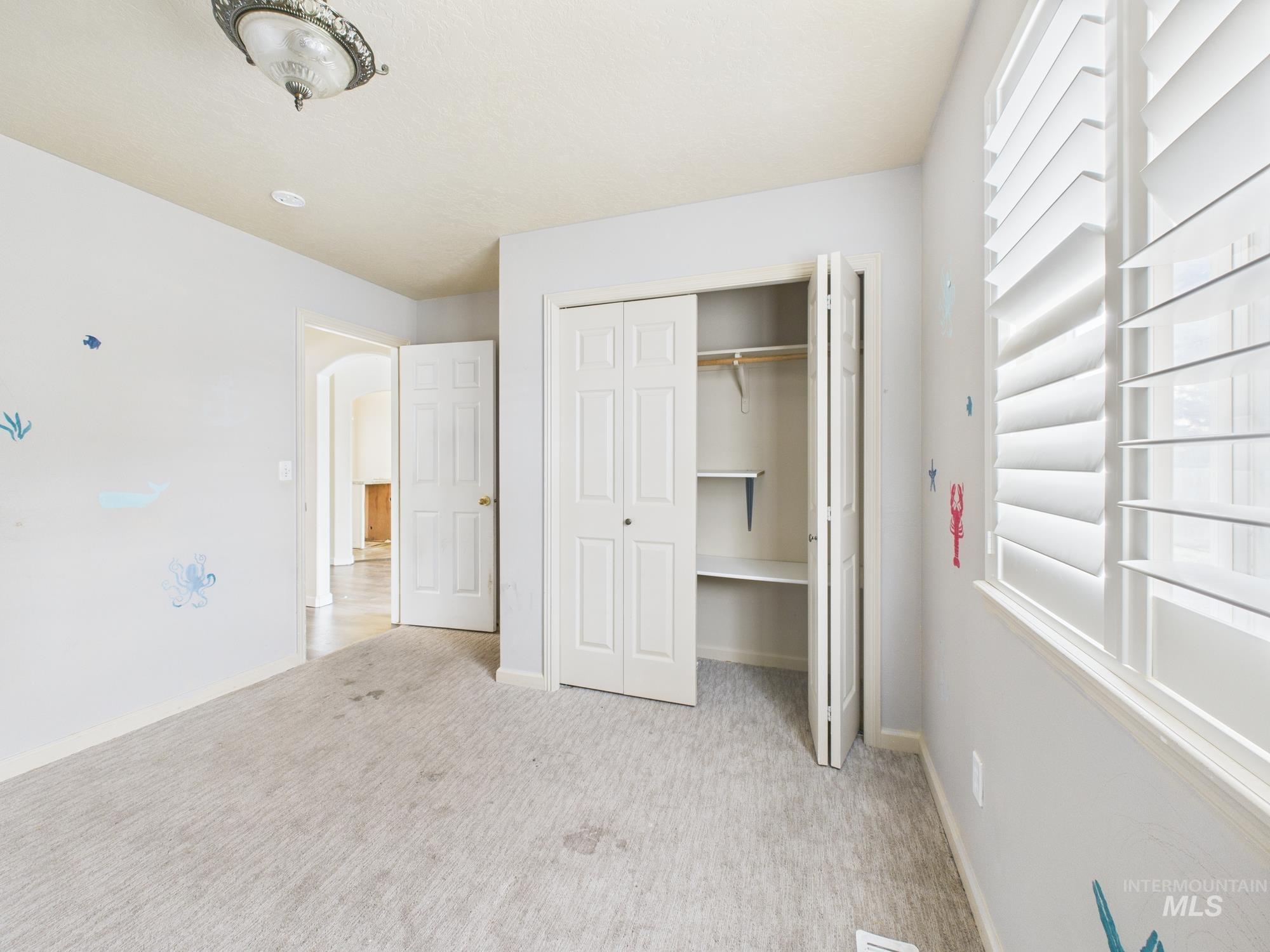 Unfurnished bedroom with light colored carpet, arched walkways, and a closet