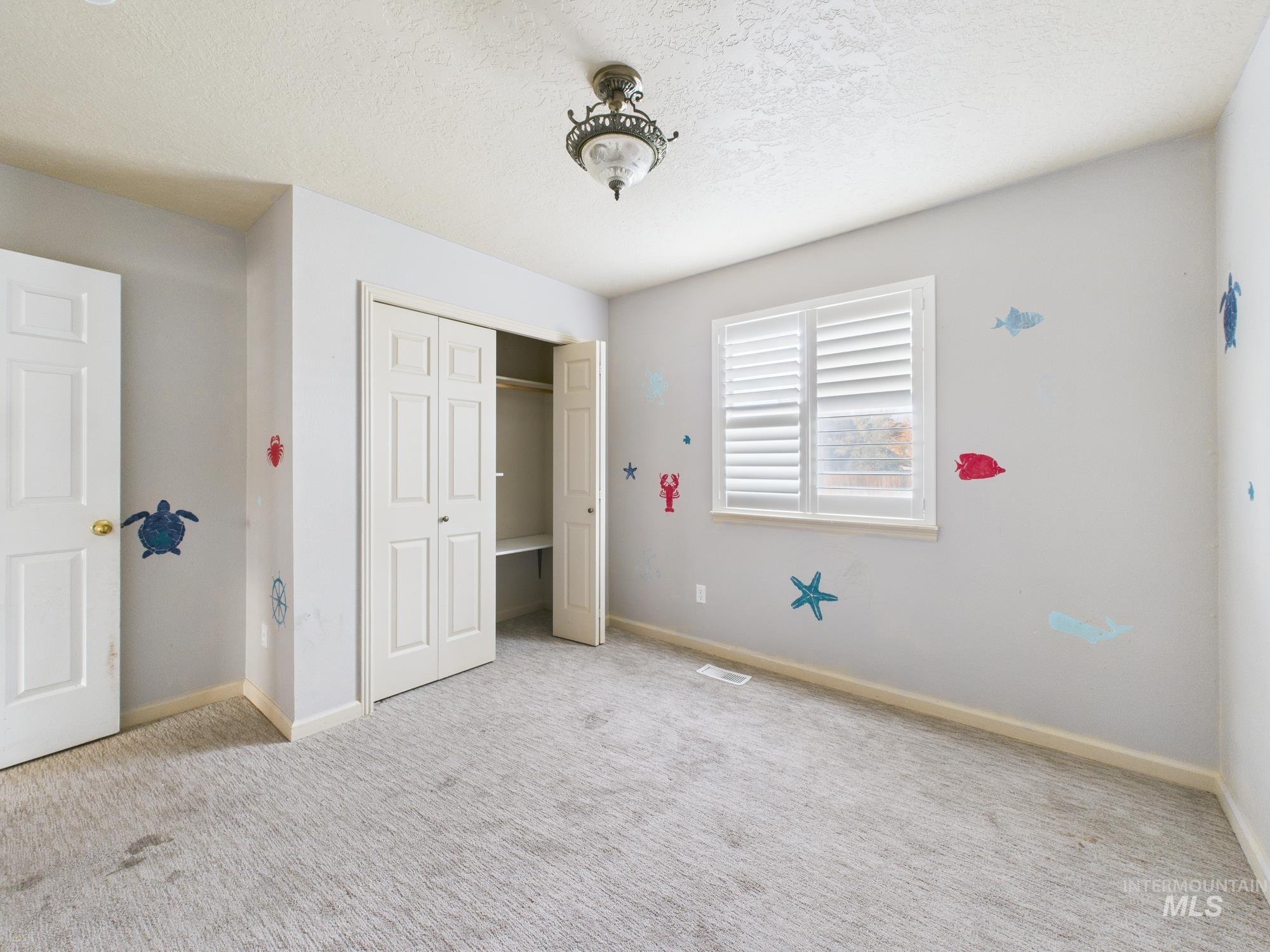 Unfurnished bedroom featuring a textured ceiling, light carpet, and a closet
